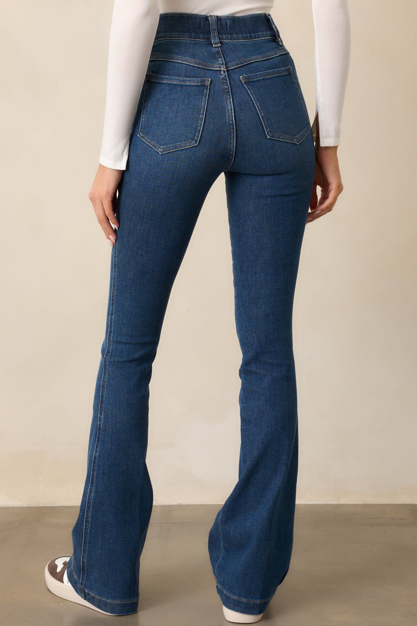 The back of the blue jeans, featuring functional back pockets and a fitted design that transitions into a flare at the hem.