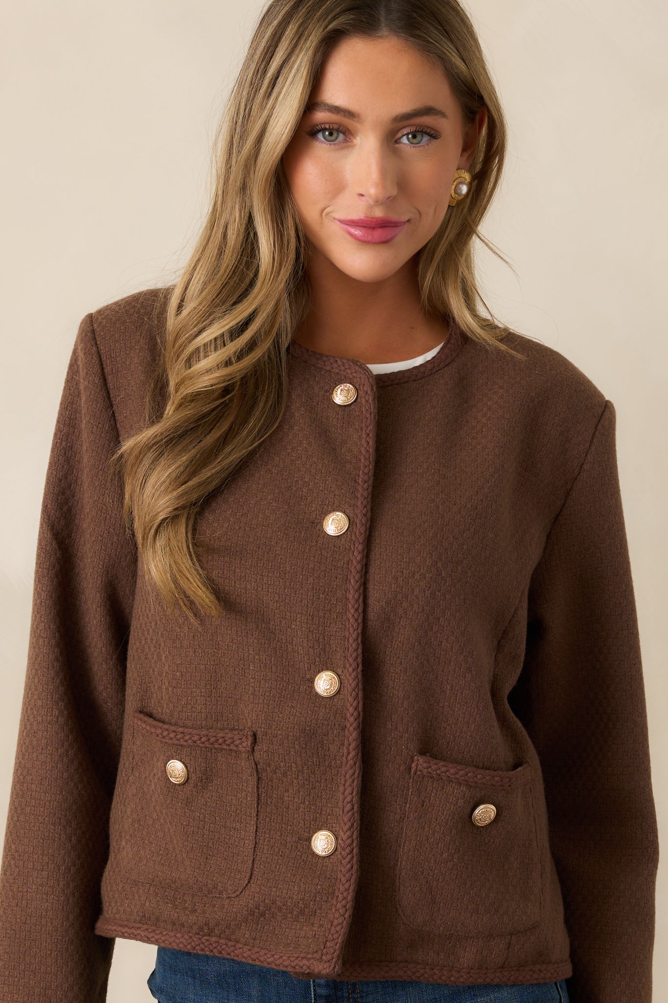 Close-up crop highlighting the tweed texture and the functional buttons on the front of the chocolate brown jacket.