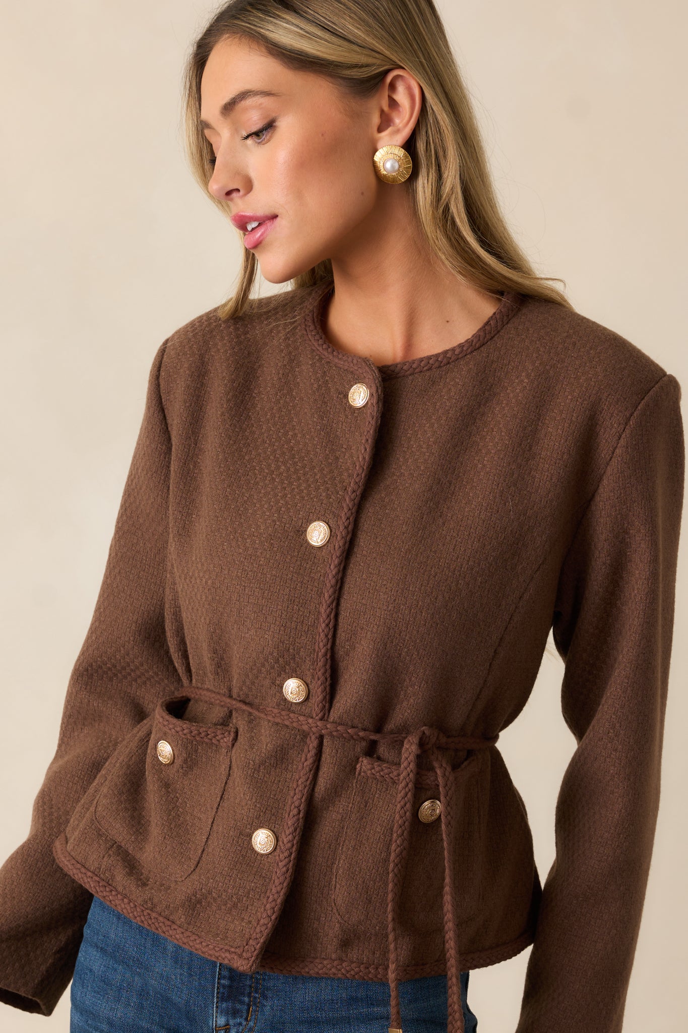 Cropped image showcasing the functional waist pockets and the self-tie braided belt detail on the chocolate brown jacket.