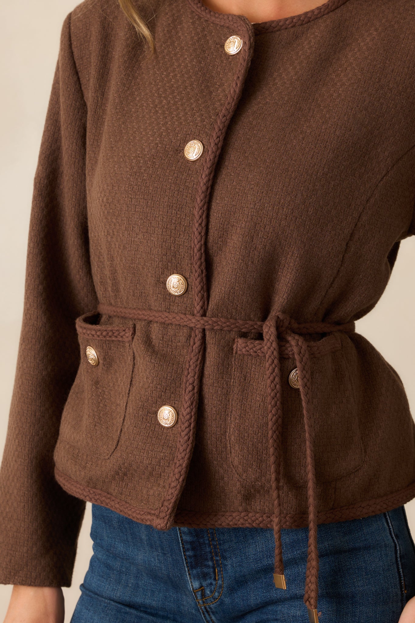 Detailed close-up showing the braided trim and textured tweed fabric near the neckline and shoulder of the chocolate brown jacket.