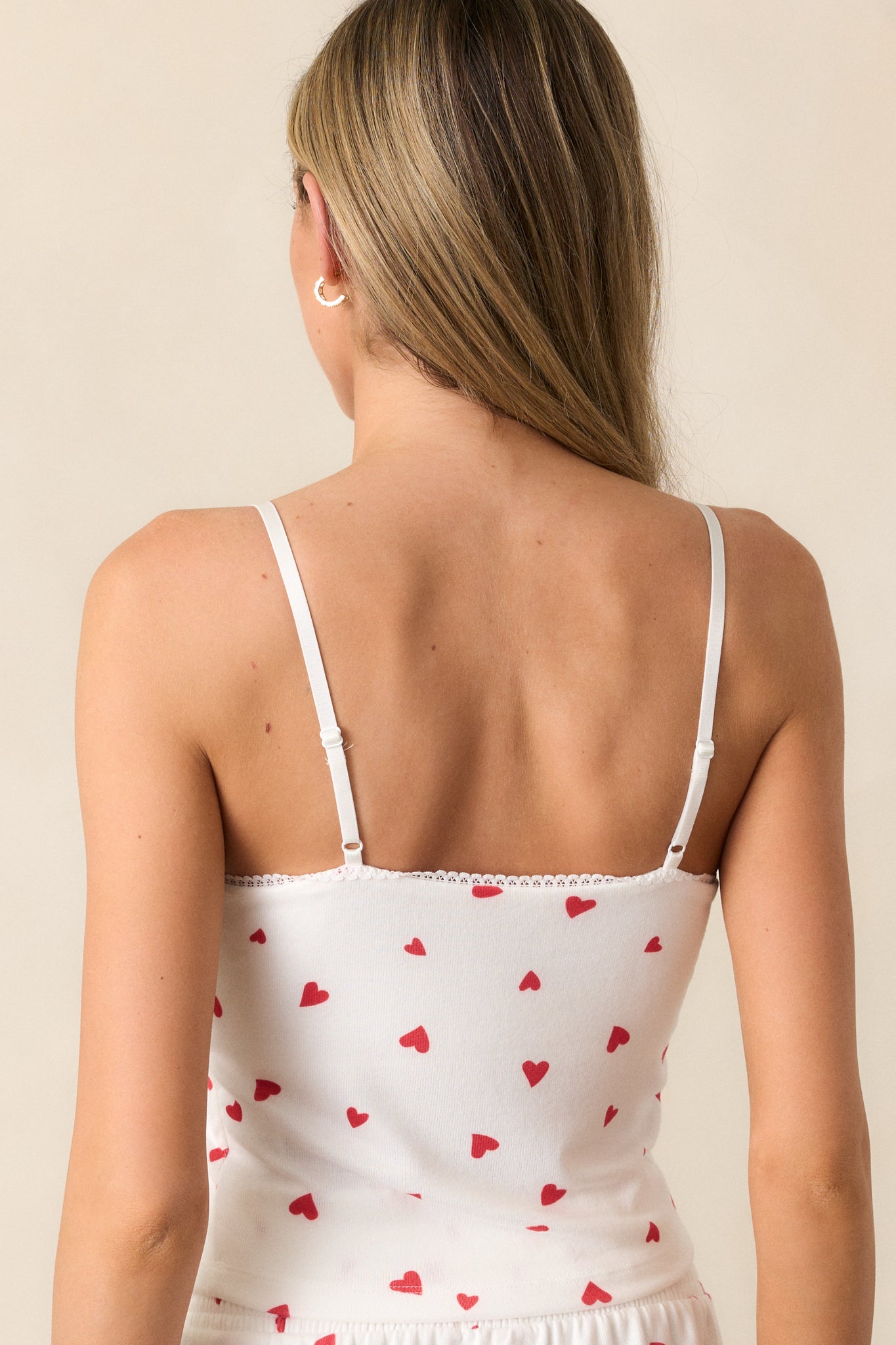 The back of the ivory cami, featuring adjustable spaghetti straps and a clean, simple design with the sprinkled red hearts.