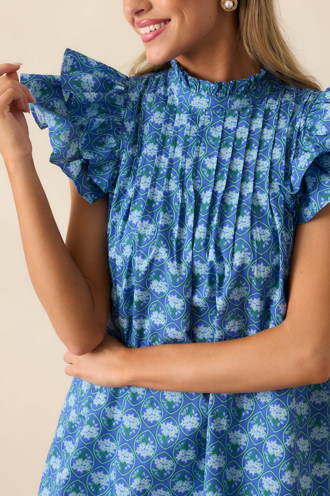 An up-close detail shot of the floral pattern and pleated yoke detailing on the navy mini dress.