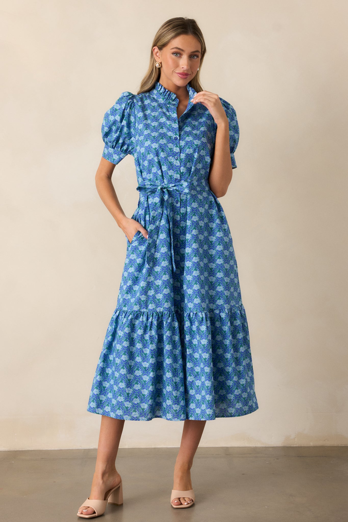 The blue dress in a full-length shot, highlighting its midi length, tiered skirt, and button front design.