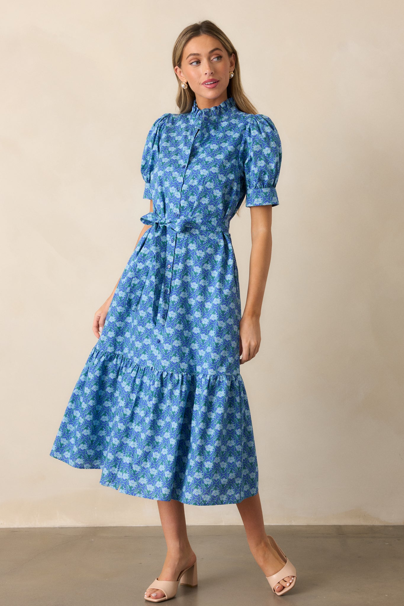 A full-length display of the blue dress, showcasing the high ruffle collar, self-tie waistband, and tiered skirt.