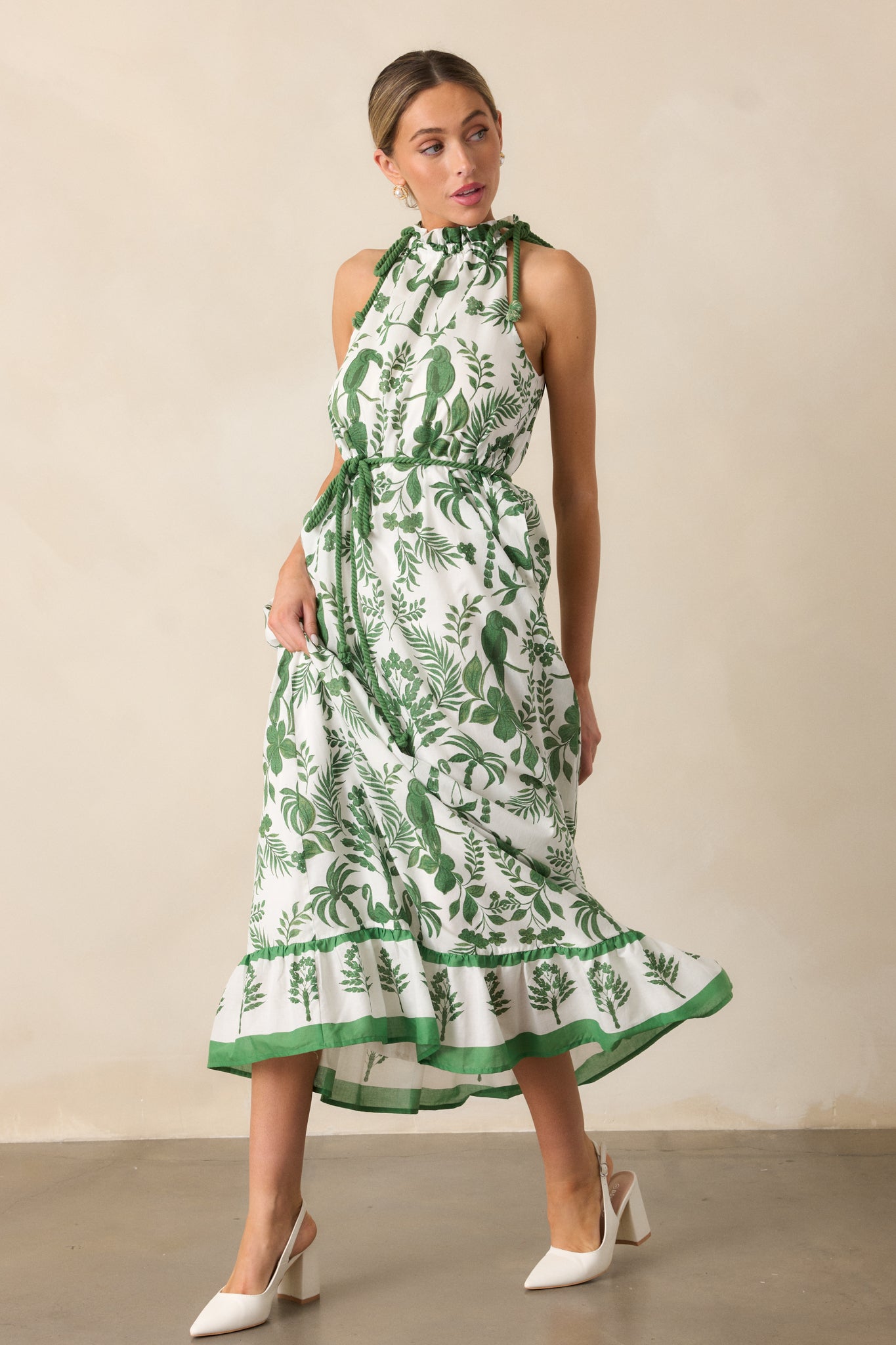 A full view of the green dress showcasing its halter neckline, self-tie cinch rope accent, and beautiful tropical print.