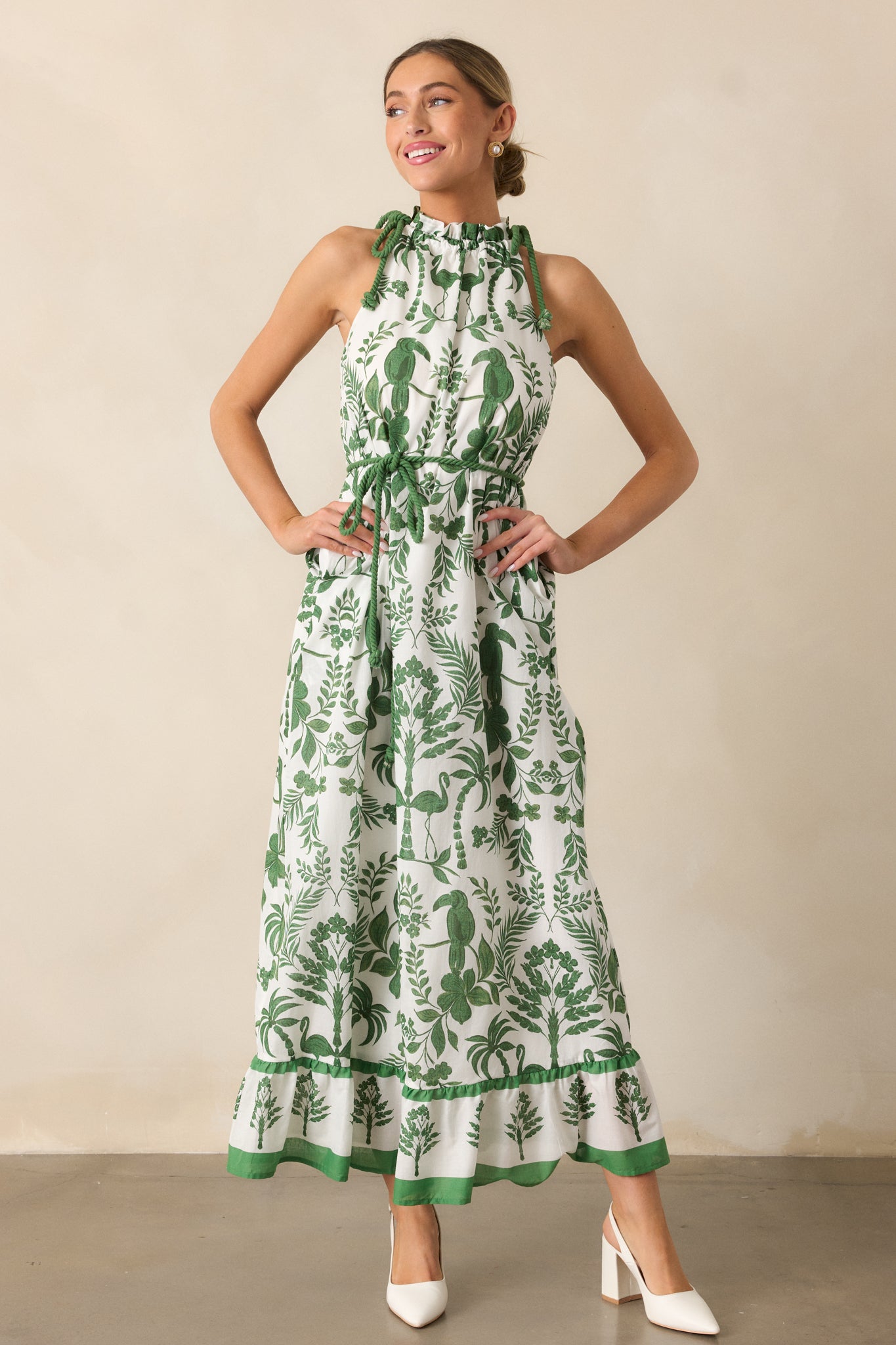 A complete look at the green dress with a halter neckline, tropical print, and maxi length with tiered details.