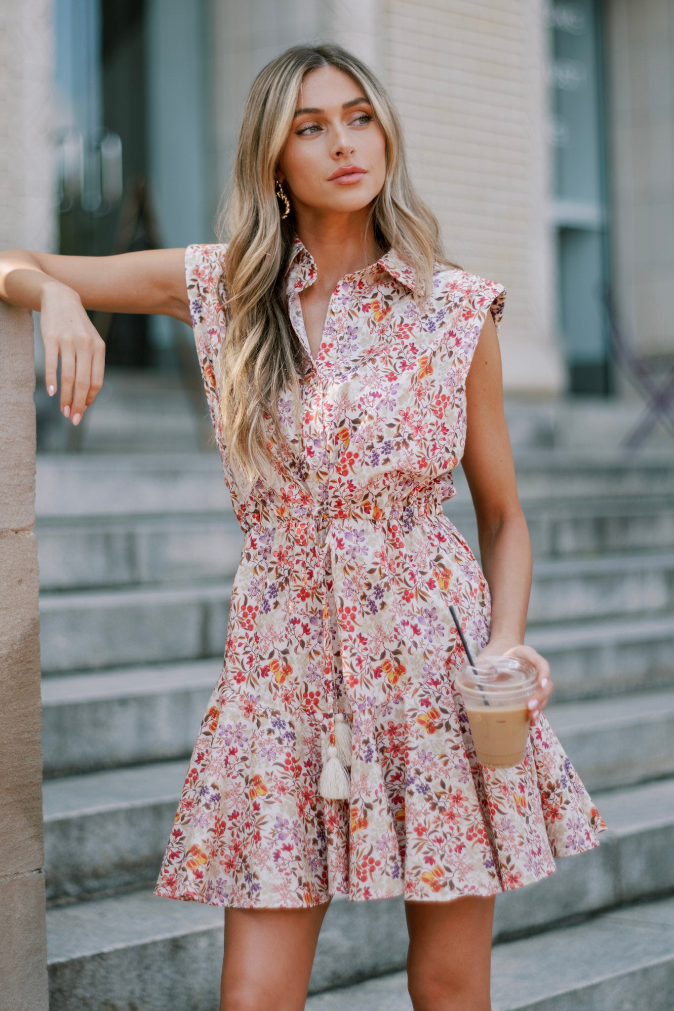 Detailed look at the beige floral mini dress's collared neckline, buttoned bust, and sleeveless padded shoulders.