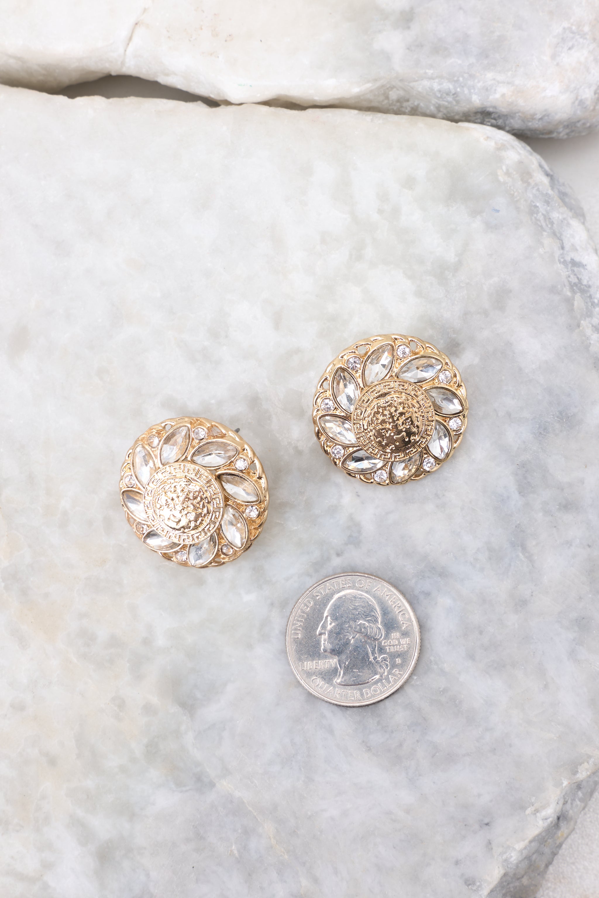 Overhead close up view of gold textured stud earrings that measure approximately 1" in diameter.