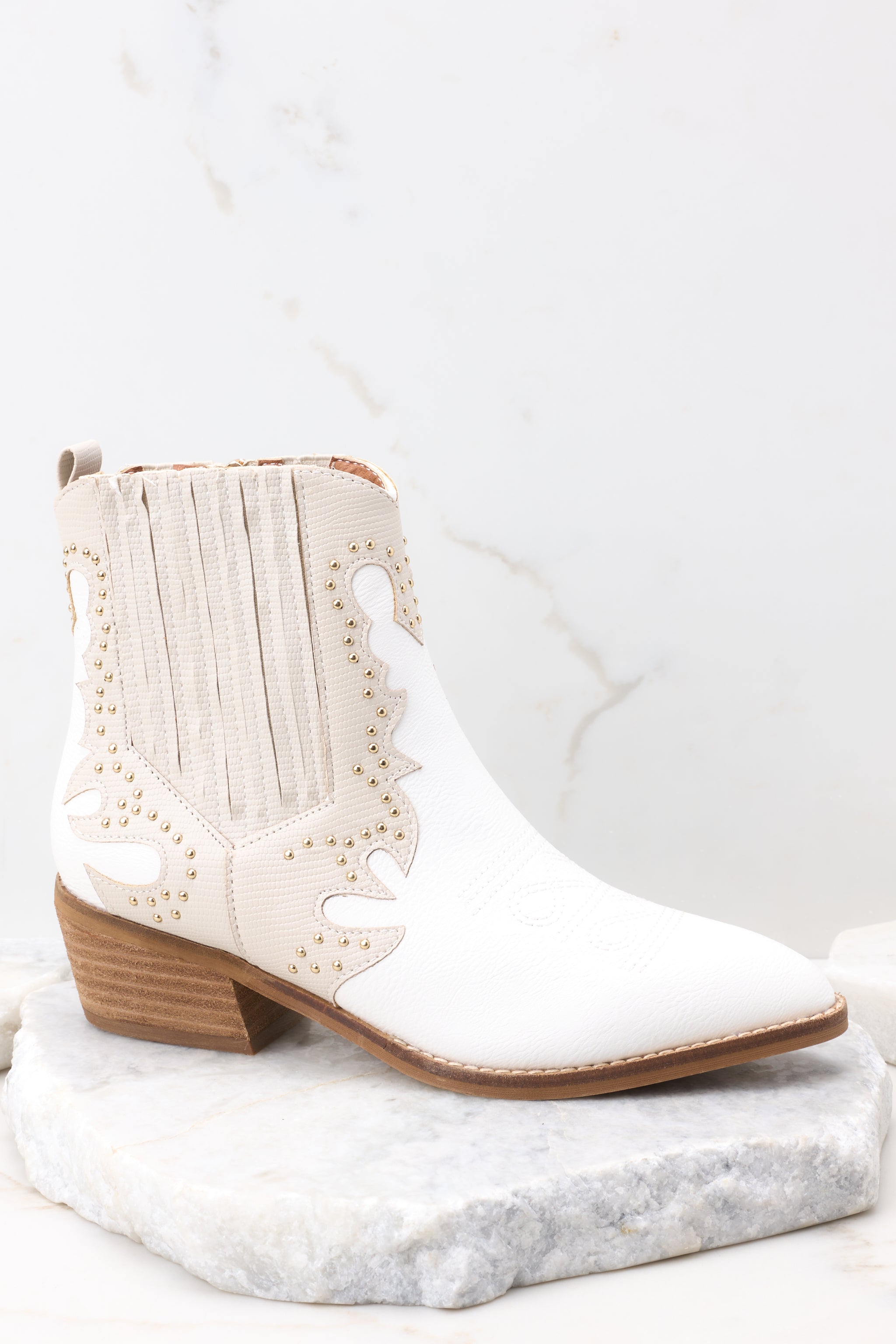 Outer-side view of these ankle boots that feature a pointed toe, a side zipper closure, a stretchy side panel, embroidered detailing, and a stacked heel.