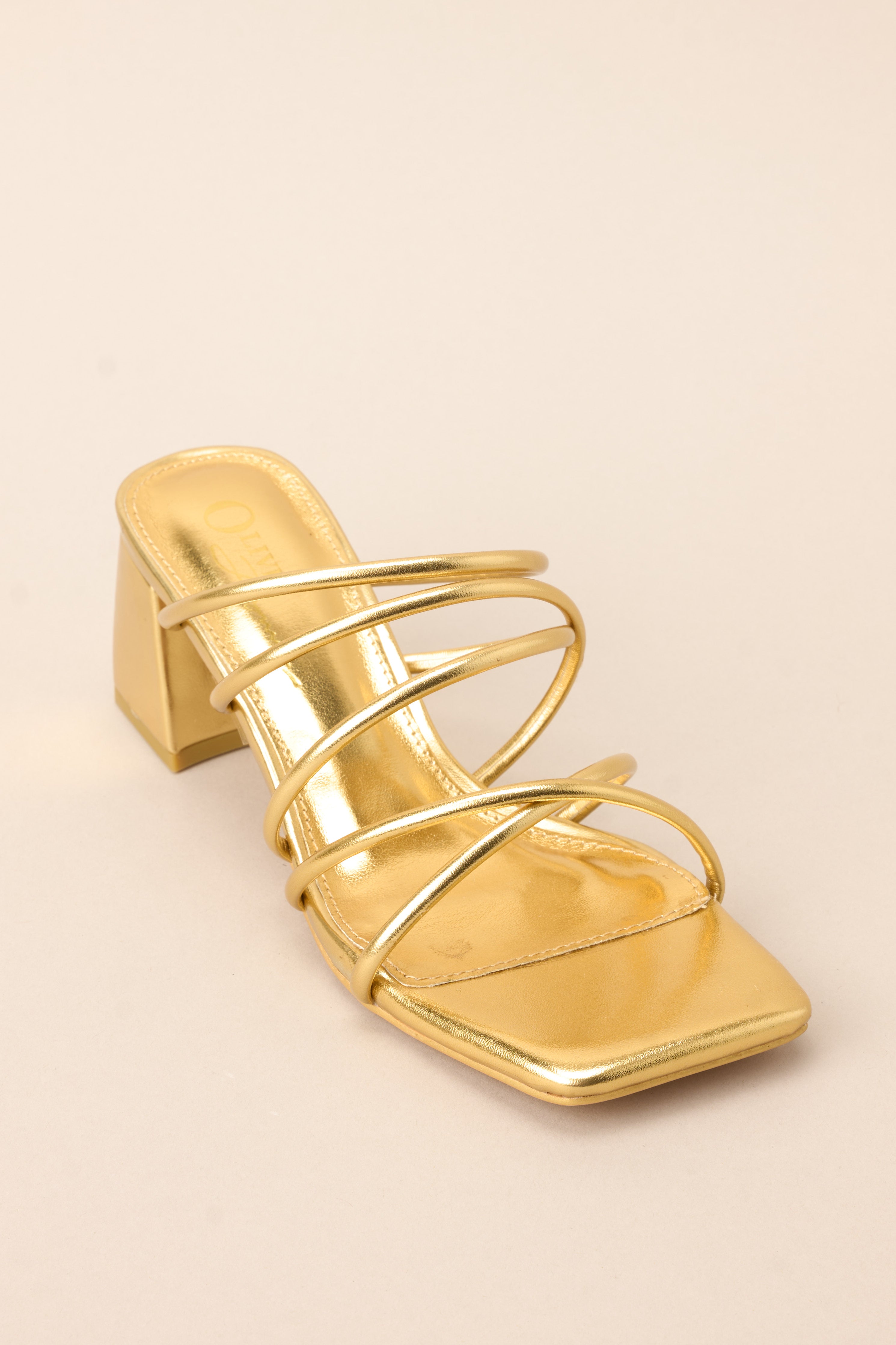 Angled front view of these heels that feature a rounded toe, a slip-on design crisscross straps across the top of the foot, and a short, thick heel.