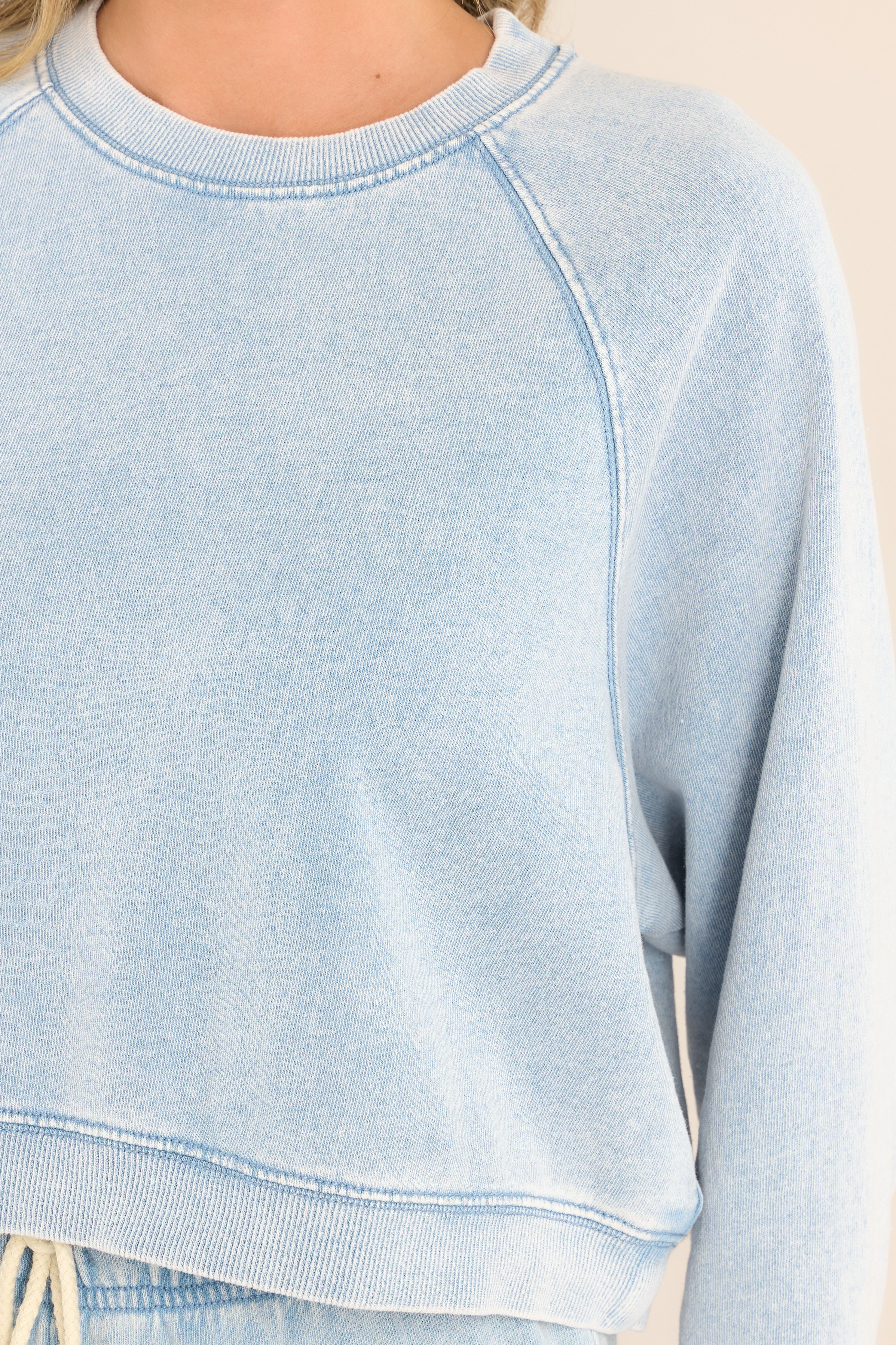 Close up view of this sweatshirt that features a ribbed crew neckline, exposed seams, a washed design, ribbed cuffed long sleeves, and a cropped hemline.