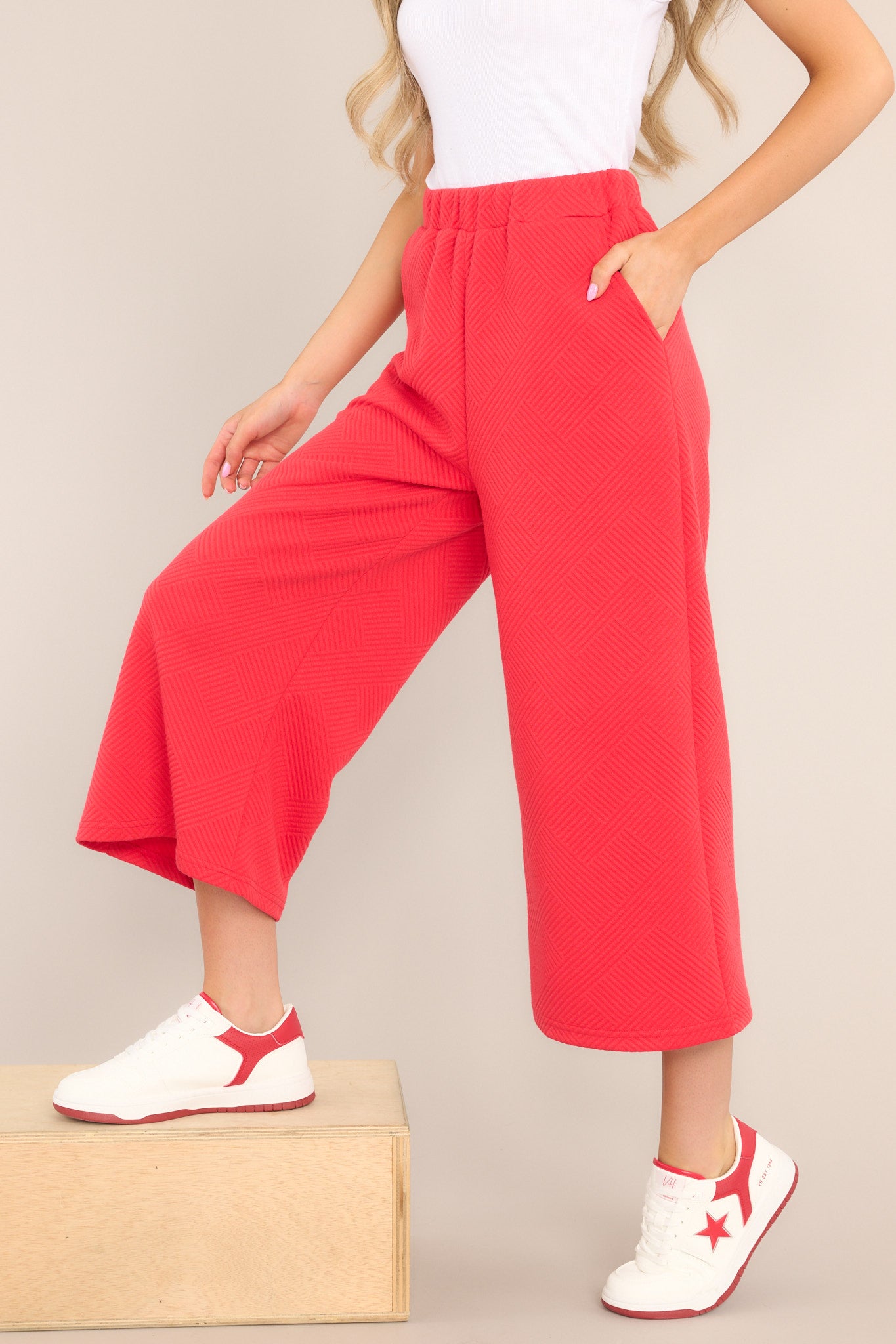 These red pants feature a high waisted design, an elastic waistband, functional hip pockets, a textured crisscross design, and a wide leg.