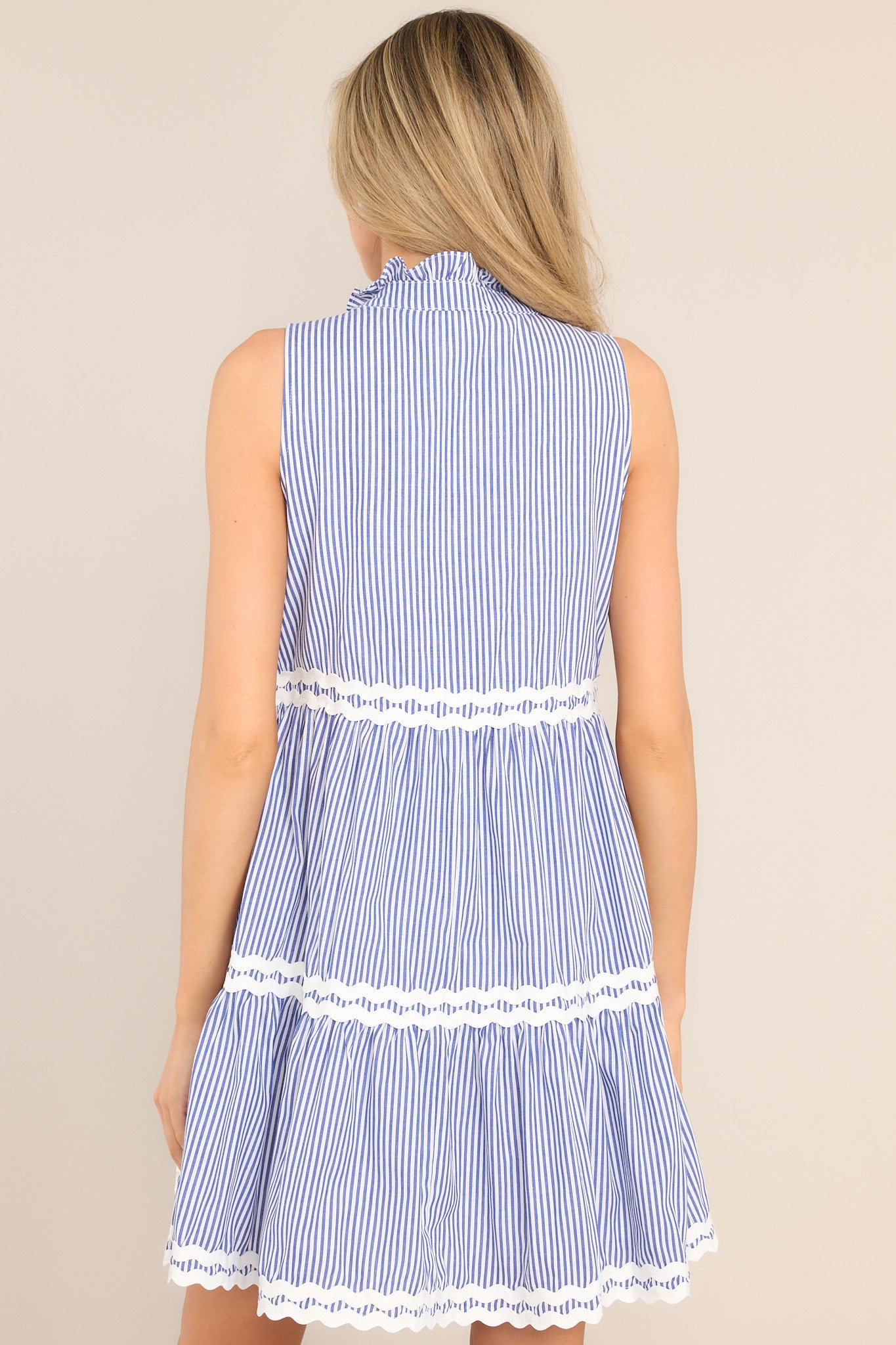 Back view of this dress that features a ruffled v-neckline, scallop detailing, functional hip pockets, and a scalloped hemline.