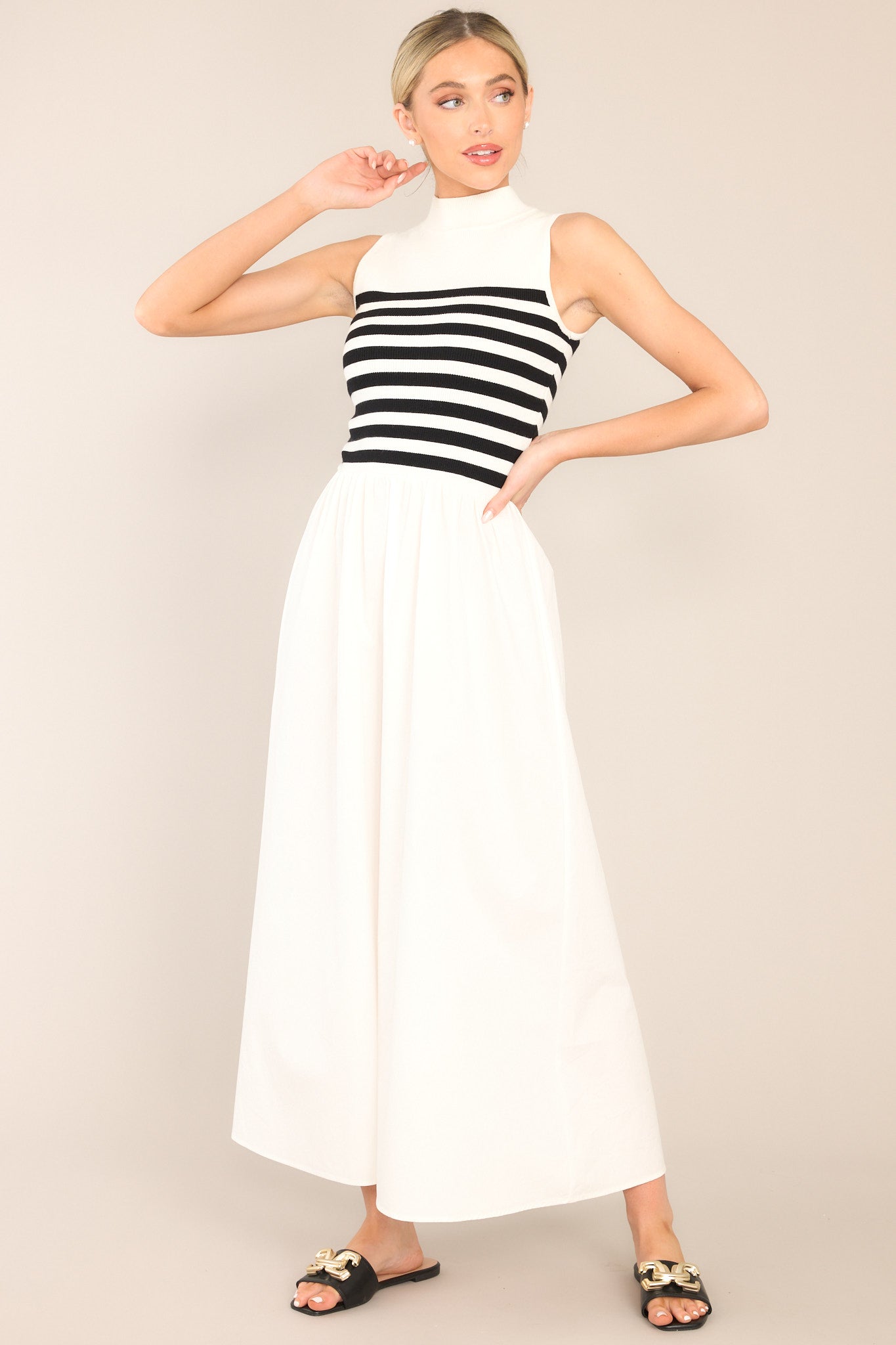 Angled front view of this dress that features a high neckline, a striped sweater bodice, and a flowy skirt.