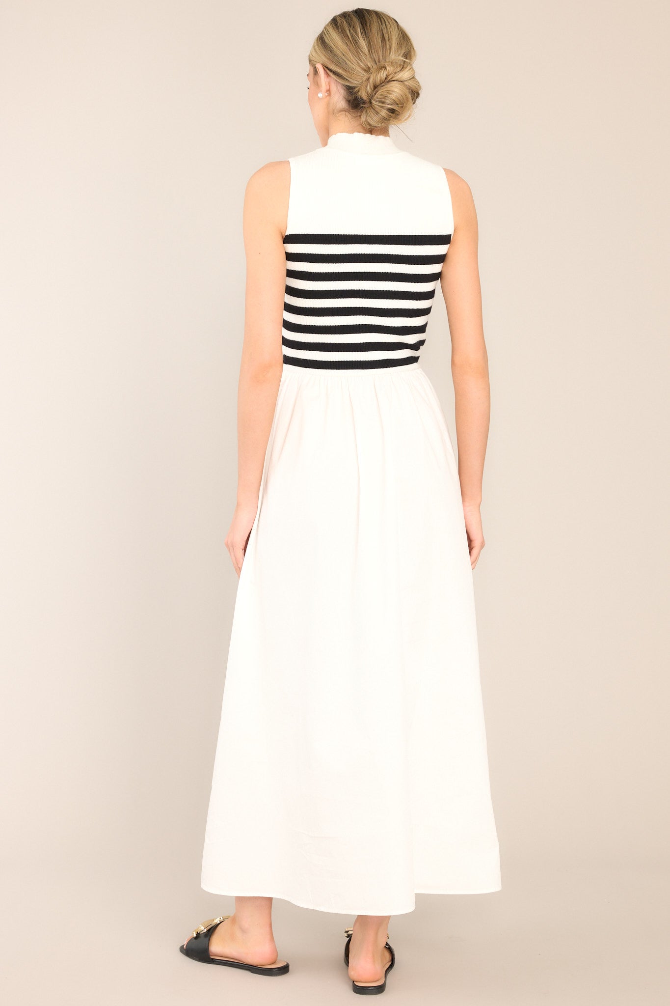 Back view of this dress that features a high neckline, a striped sweater bodice, and a flowy skirt.