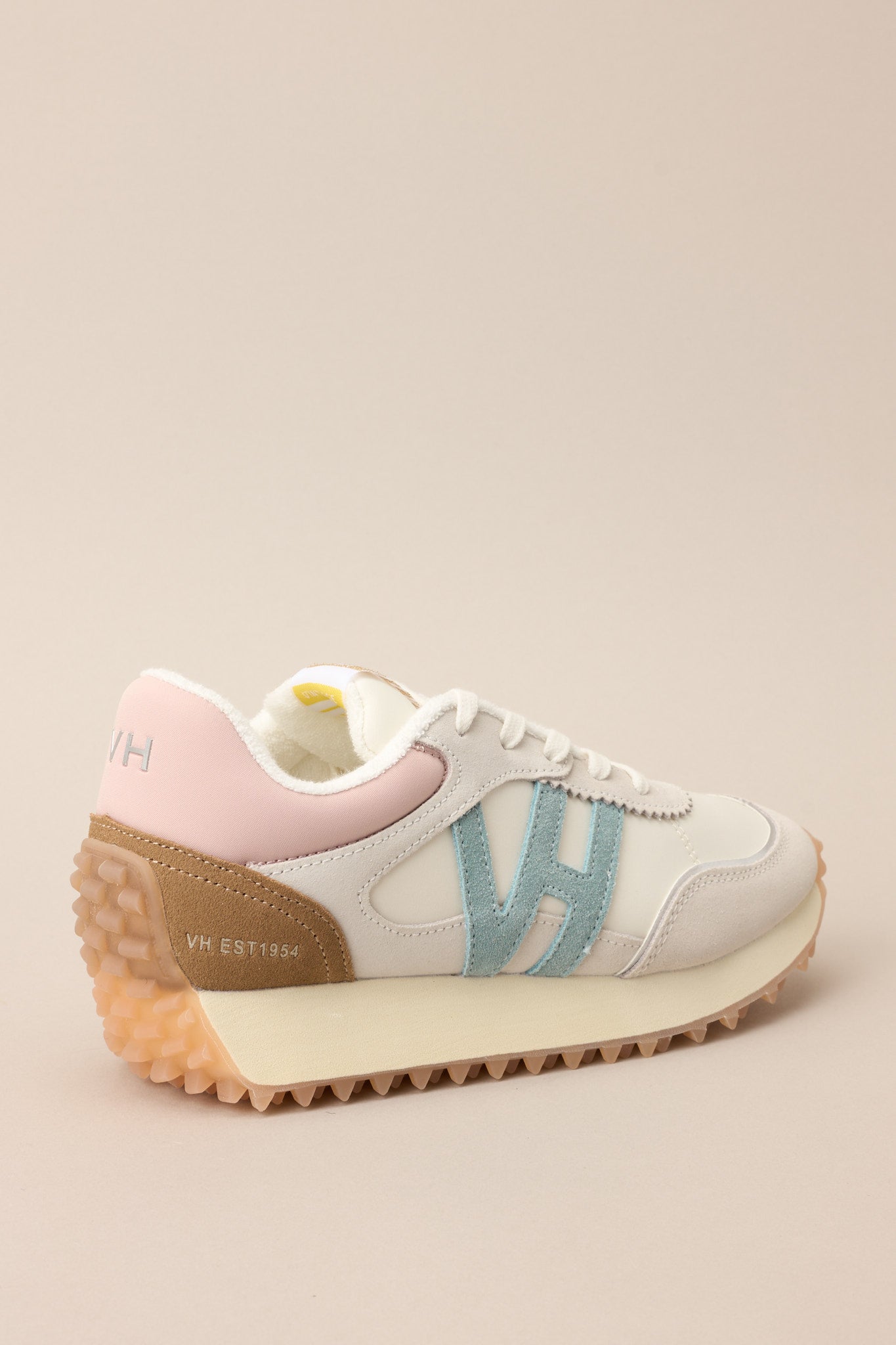 Back view of these sneakers that feature a rounded toe, functional laces, subtle pops of color, a slight platform, and a heavily textured sole.