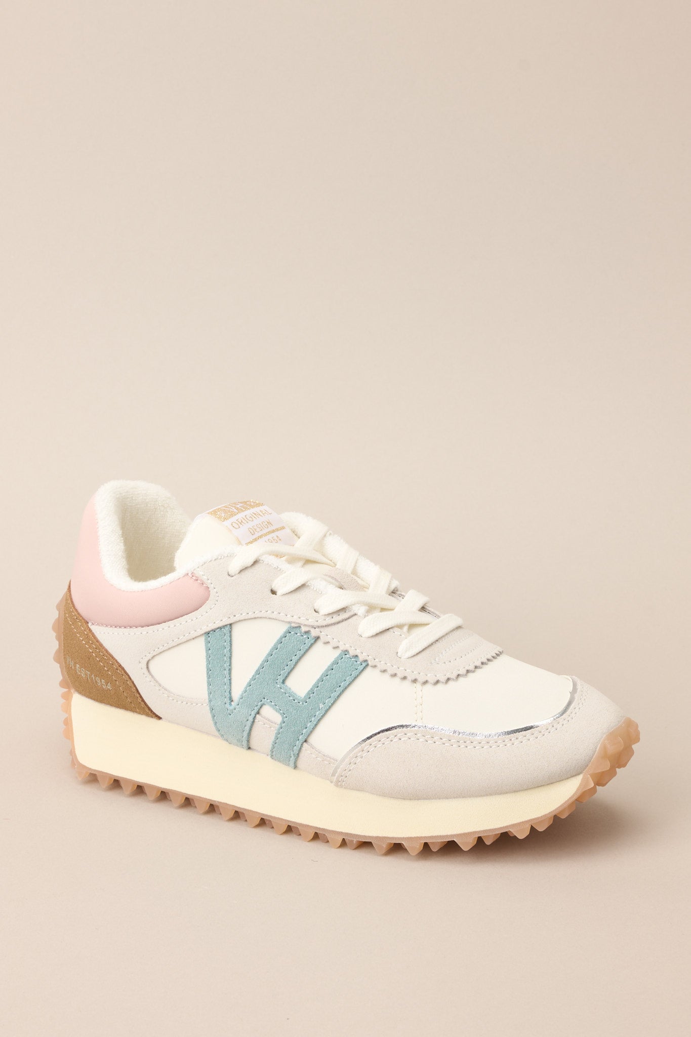 Angled outer-side view of these sneakers that feature a rounded toe, functional laces, subtle pops of color, a slight platform, and a heavily textured sole.