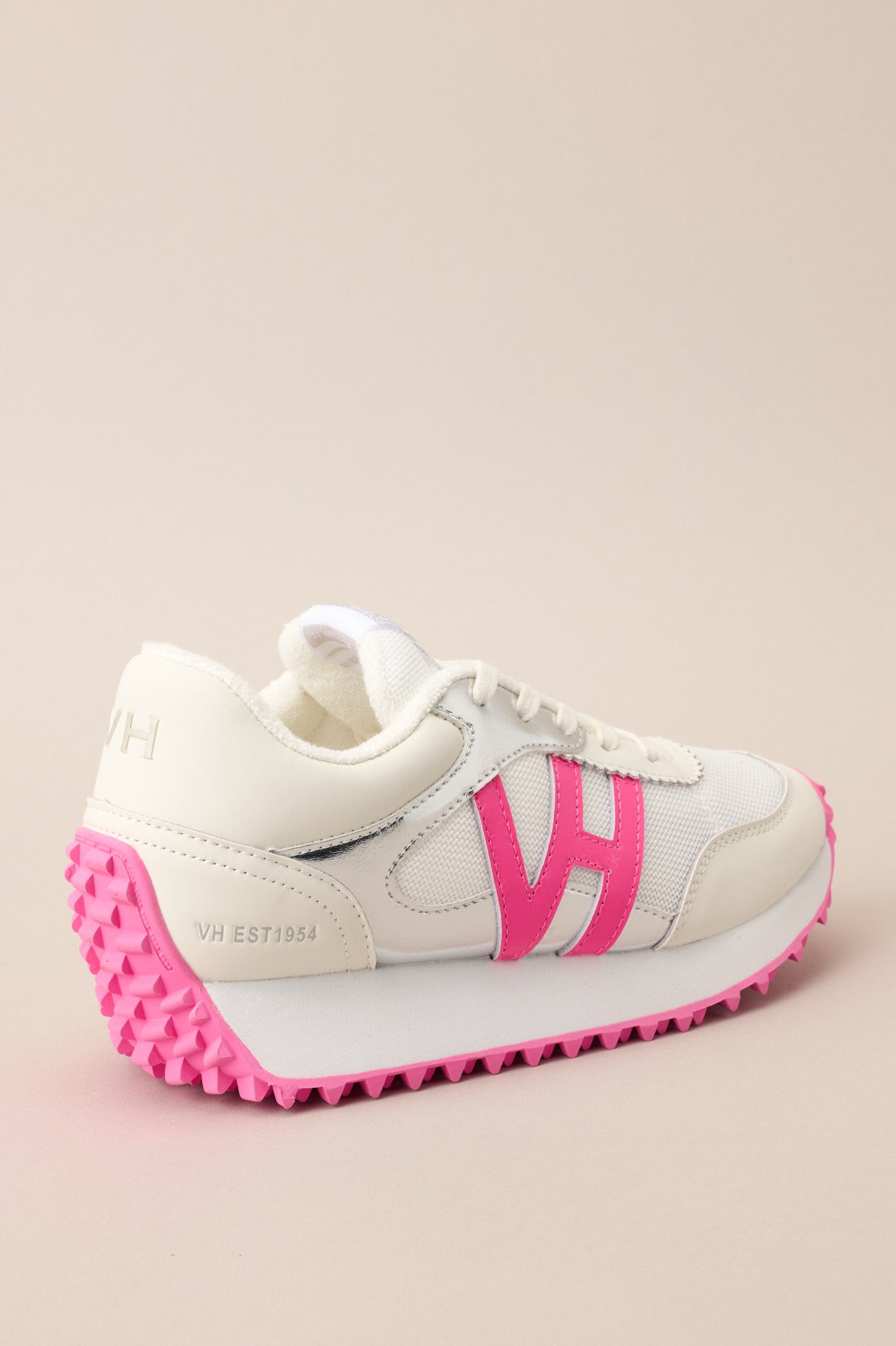 Angled back view of these sneakers that feature a rounded toe, functional laces, subtle pops of color, a slight platform, and a heavily textured sole.