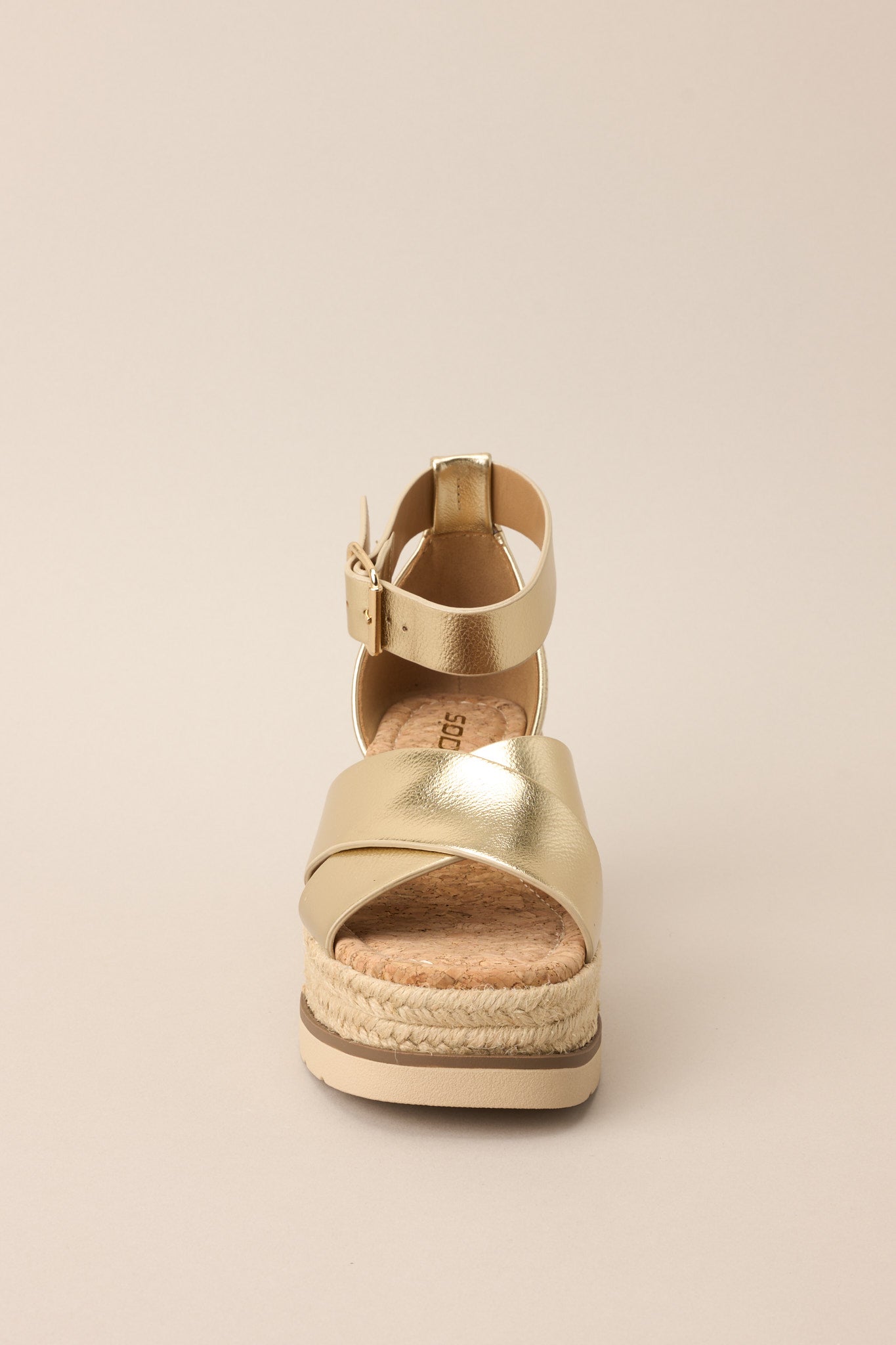 Front view of these sandals that feature a rounded toe, gold hardware, crossed straps over the top of the foot, an ankle strap with a classic buckle closure, and an espadrille wedged platform.