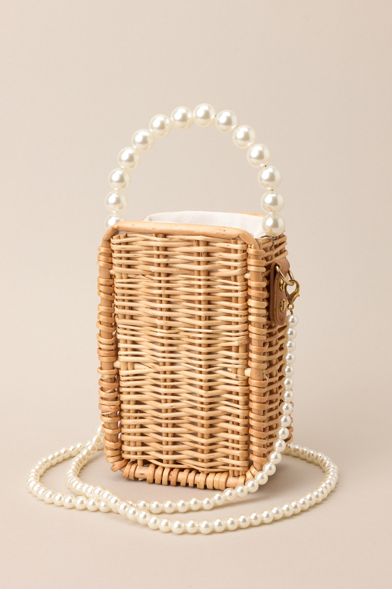 Front view of this bamboo bag that features a faux pearl top handle, a removable faux pearl strap, and a cloth drawstring closure.