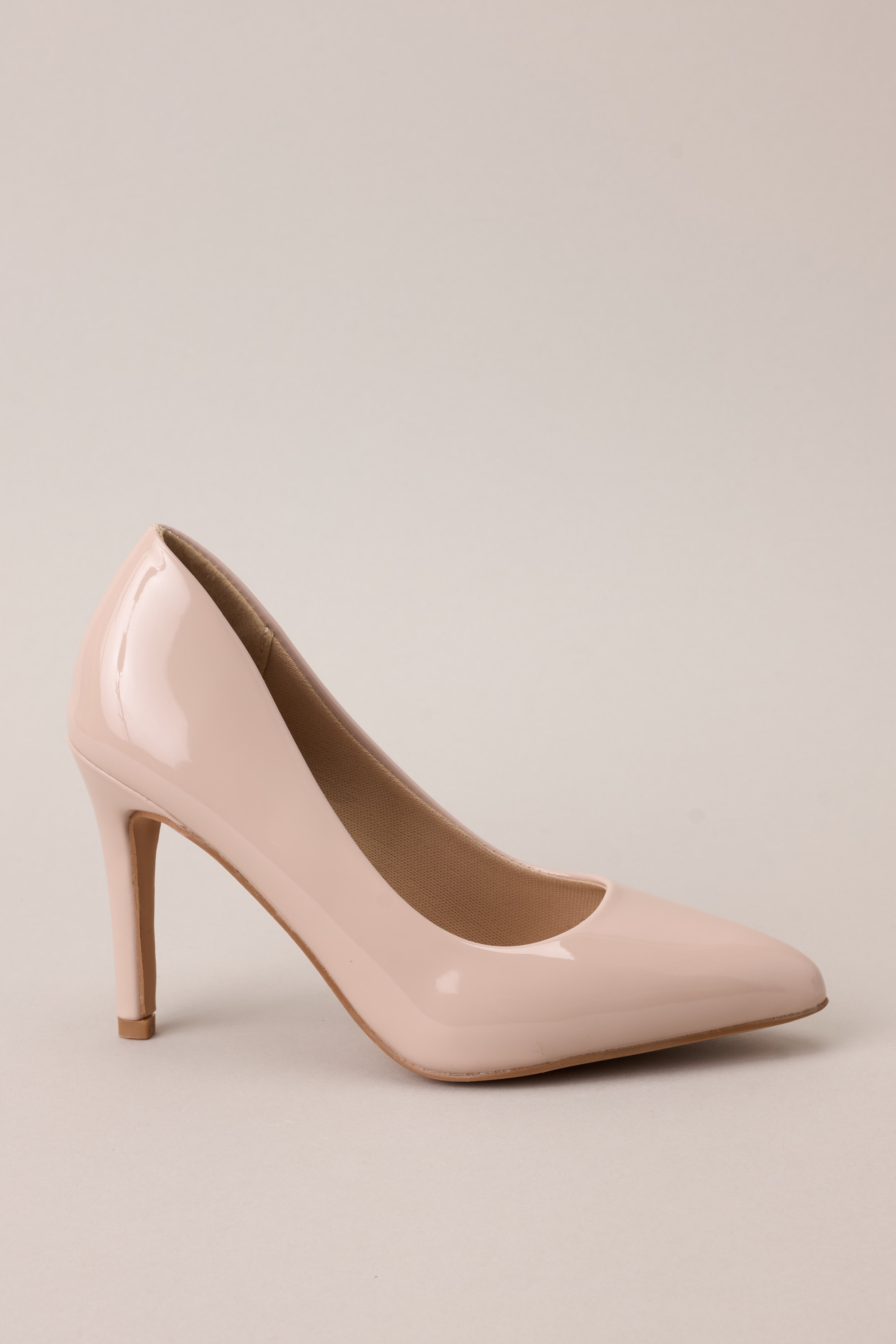 Side view of these beige heels with a pointed toe, vibrant color, glossy finish, and skinny heel.