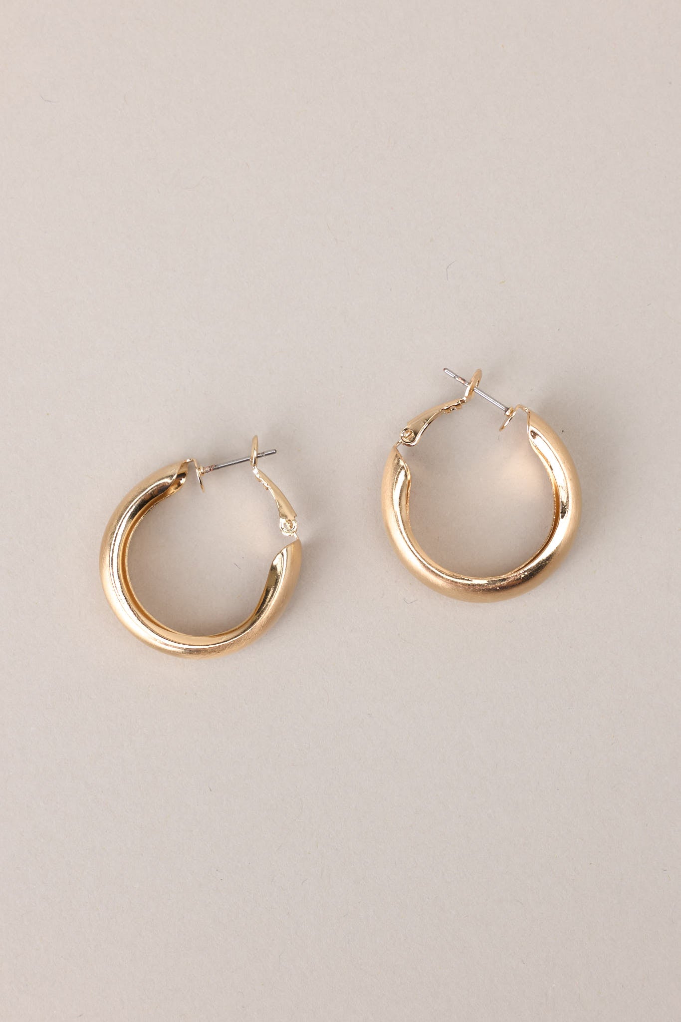 Overhead view of these earrings that feature gold hardware, a matte finish, and a functional clasp closure.