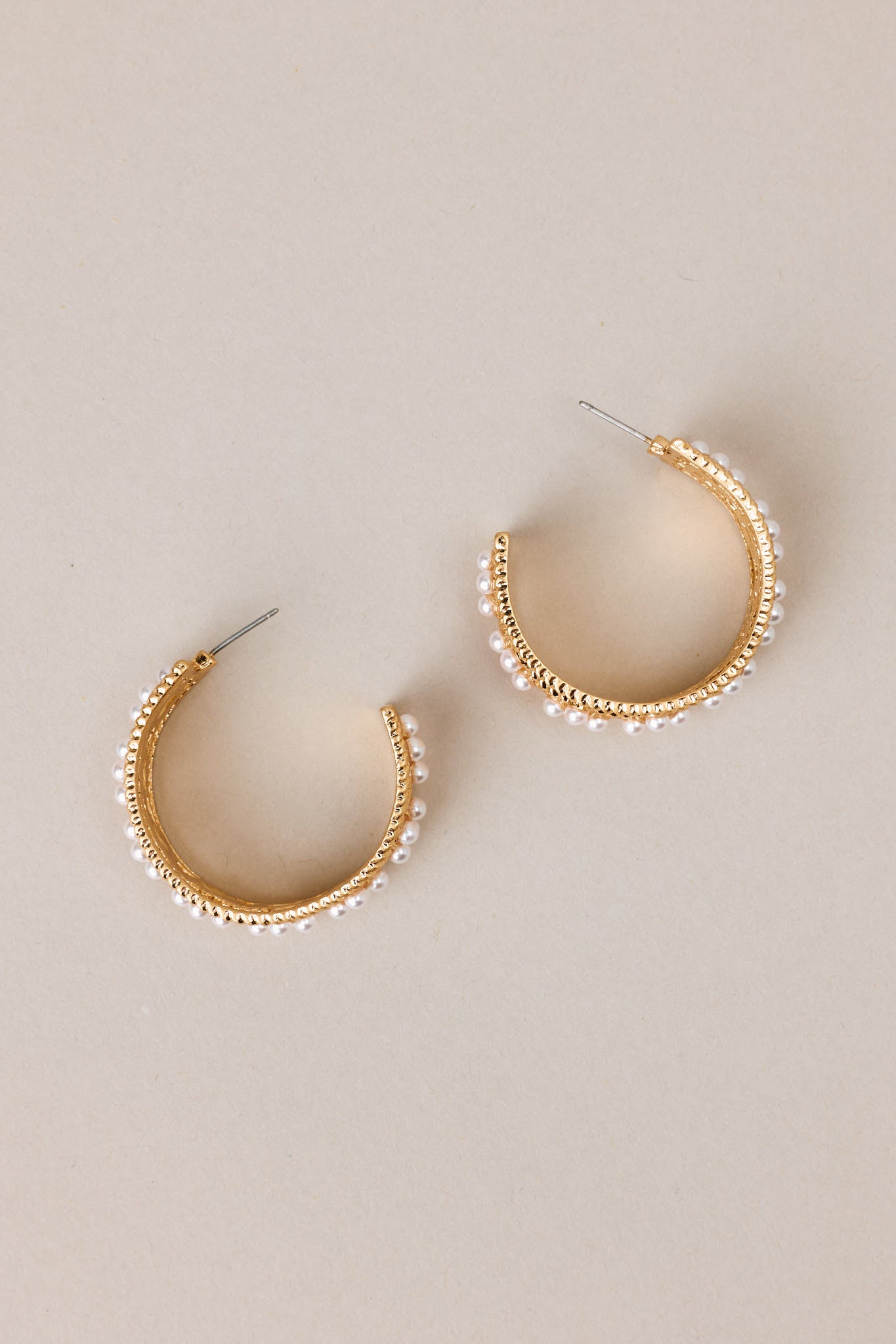 Overhead view of these hoops that feature gold hardware, faux pearl embellishments, and secure post backings.