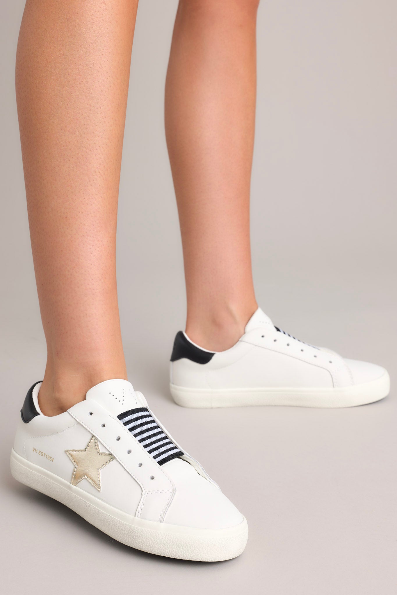 Full view of these sneakers that feature a rounded toe, a laceless design, a comfortable fit, and a star detail.