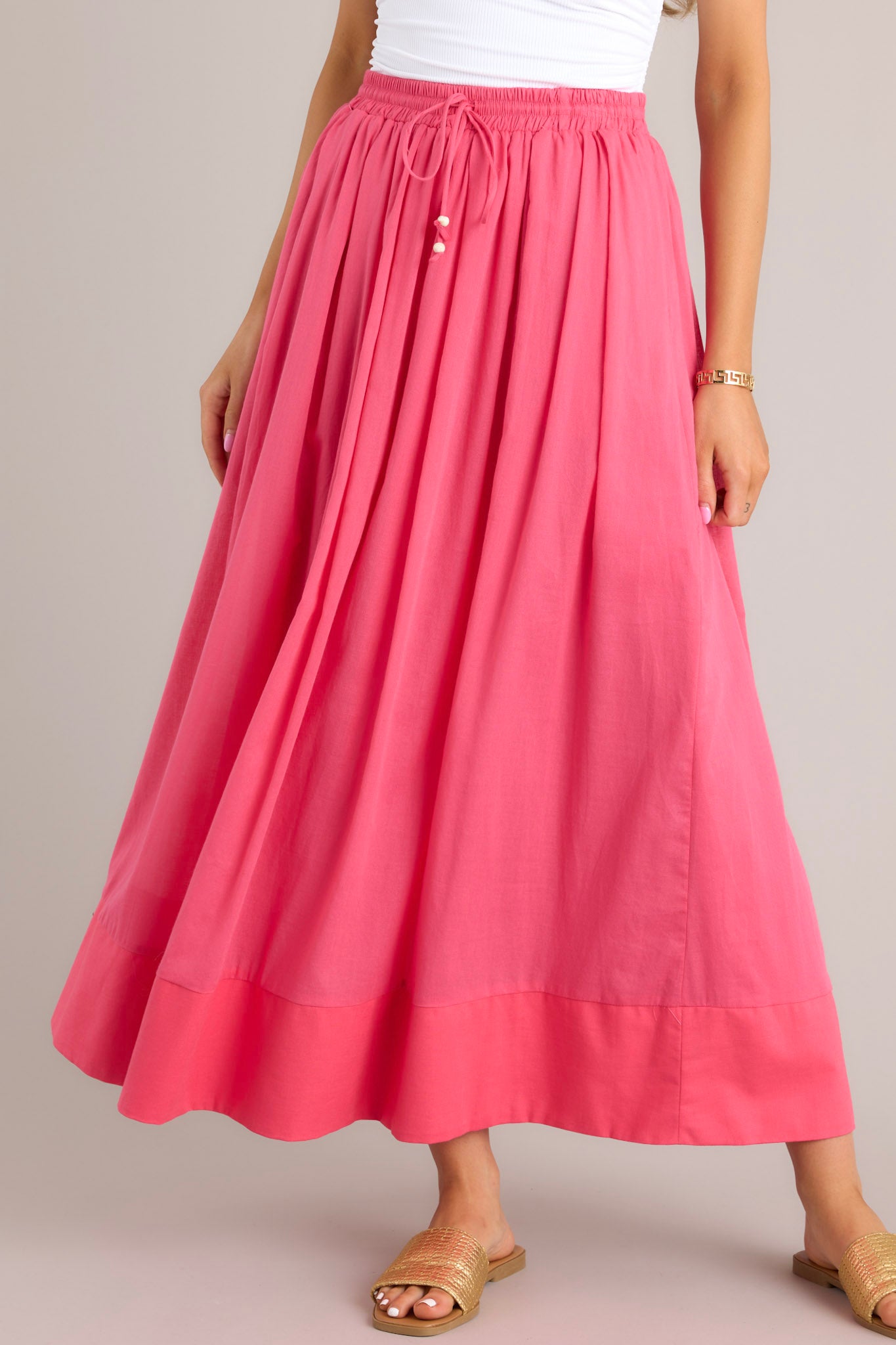 Front view of this skirt that features a high waisted design, an elastic waistband, a self-tie drawstring, functional pockets, flowing fabric, and a thick hemline.