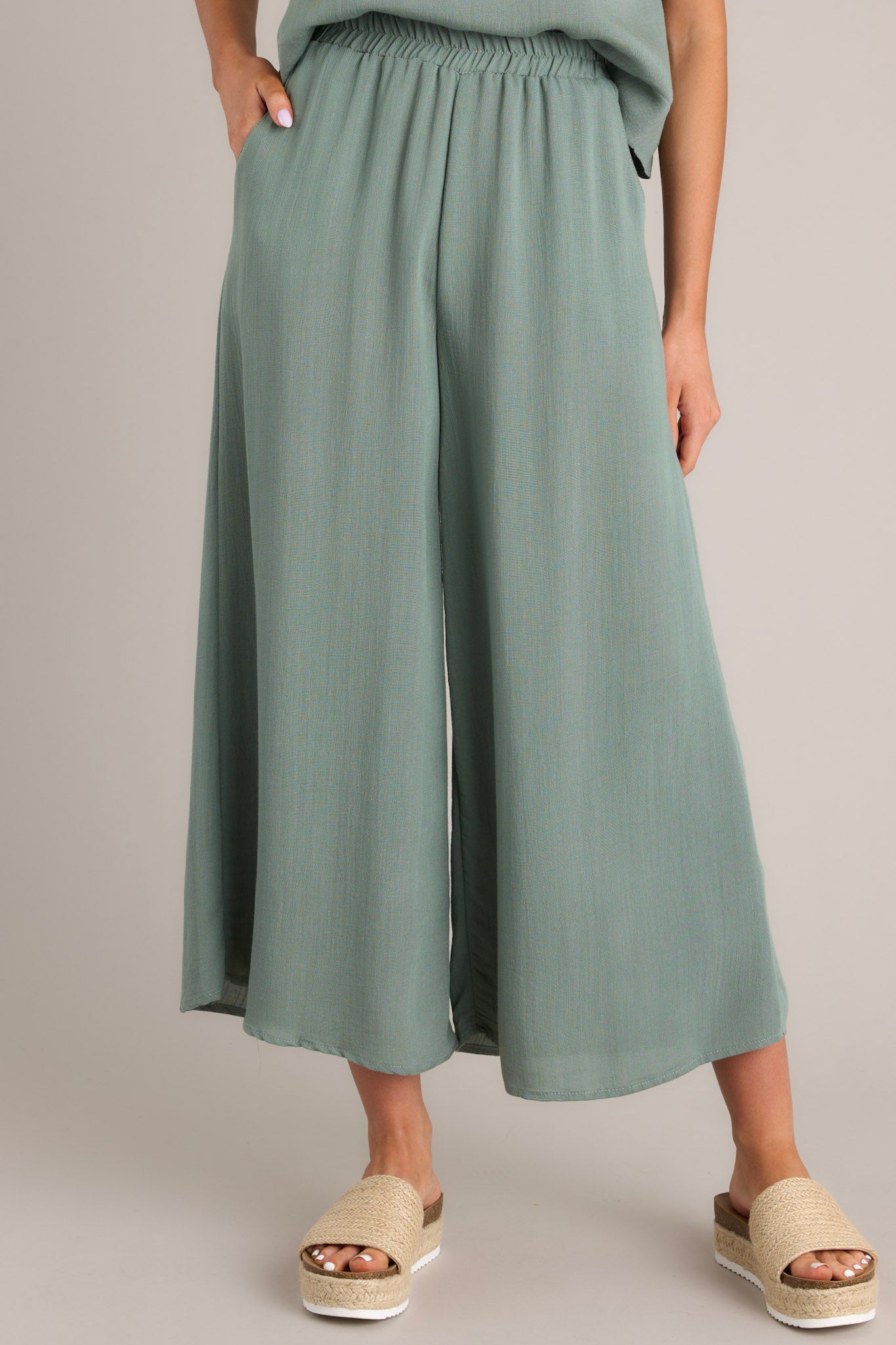 Front view of these pants that feature a high waisted design, an elastic waistband, functional hip pockets, a wide leg design, and a slightly cropped length.