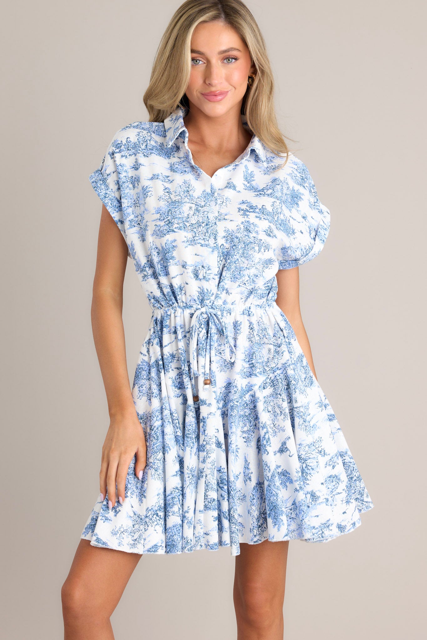 Front view of this dress that features a collared neckline, functional buttons, a self-tie waist feature, and a flowy skirt.