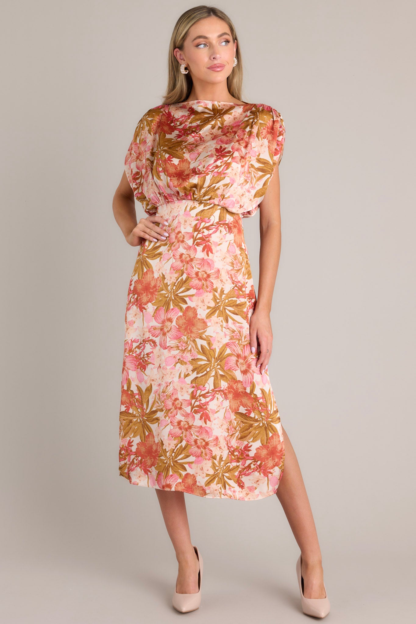 Angled full body view of this knee-length rose pink dress with a boat neckline, gathered waist, elastic insert in the back, discreet side zipper, side slit, and wide sleeves.