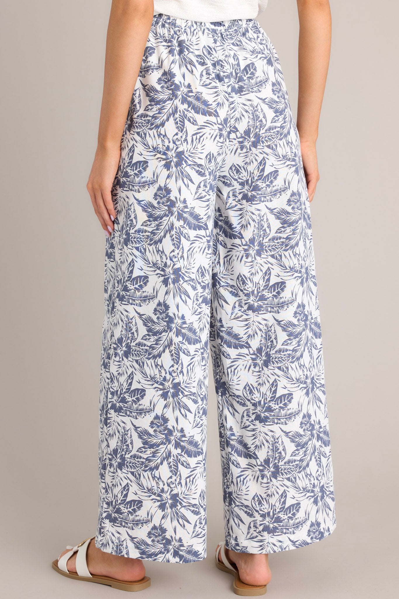 Back view of these pants that feature a high waisted design, an elastic waistband, functional hip pockets, a unique pattern, and a wide leg design.