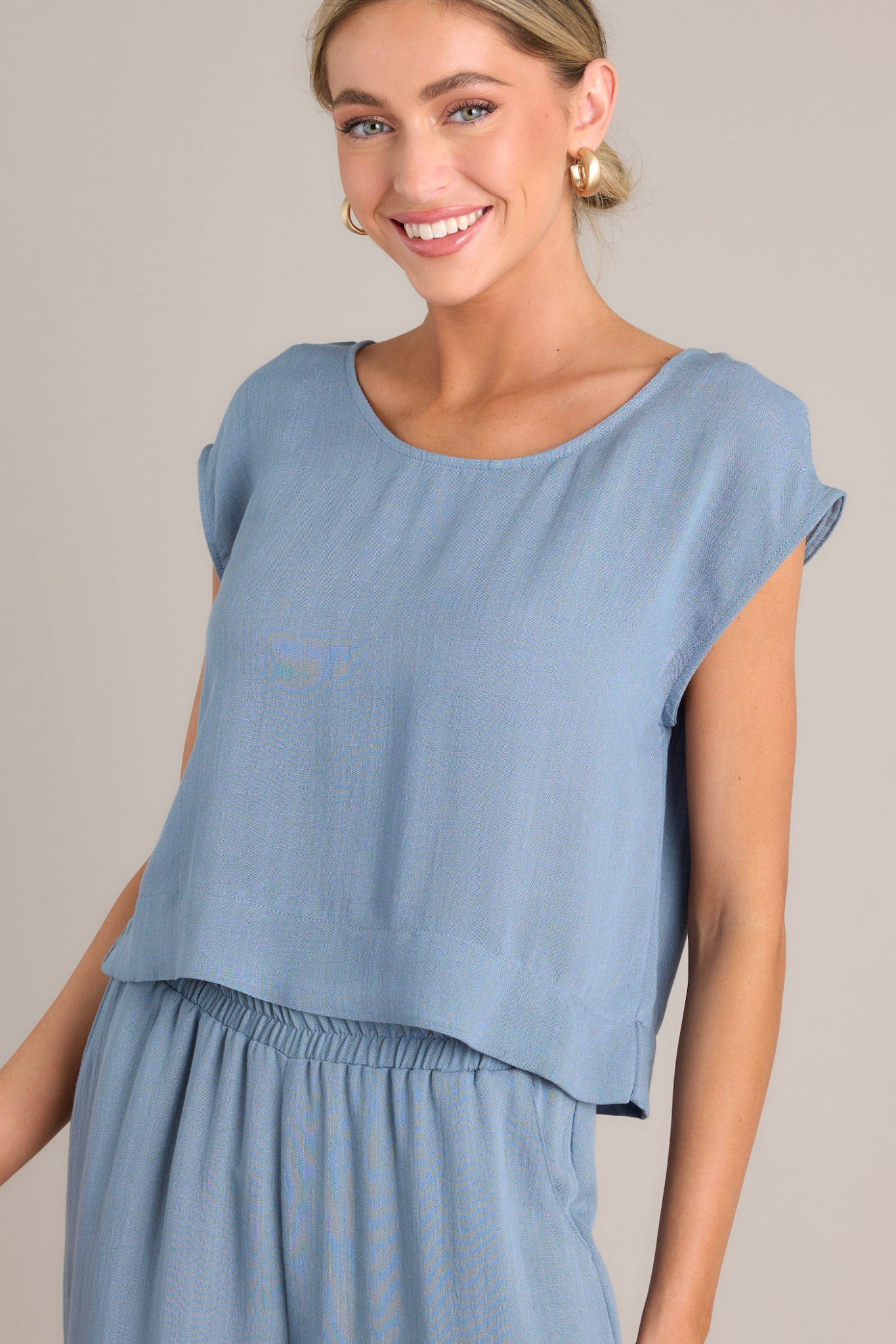 Close up view of this top that features a cap sleeve design, a crew neckline, slightly cropped length, and breezy lightweight fabric.