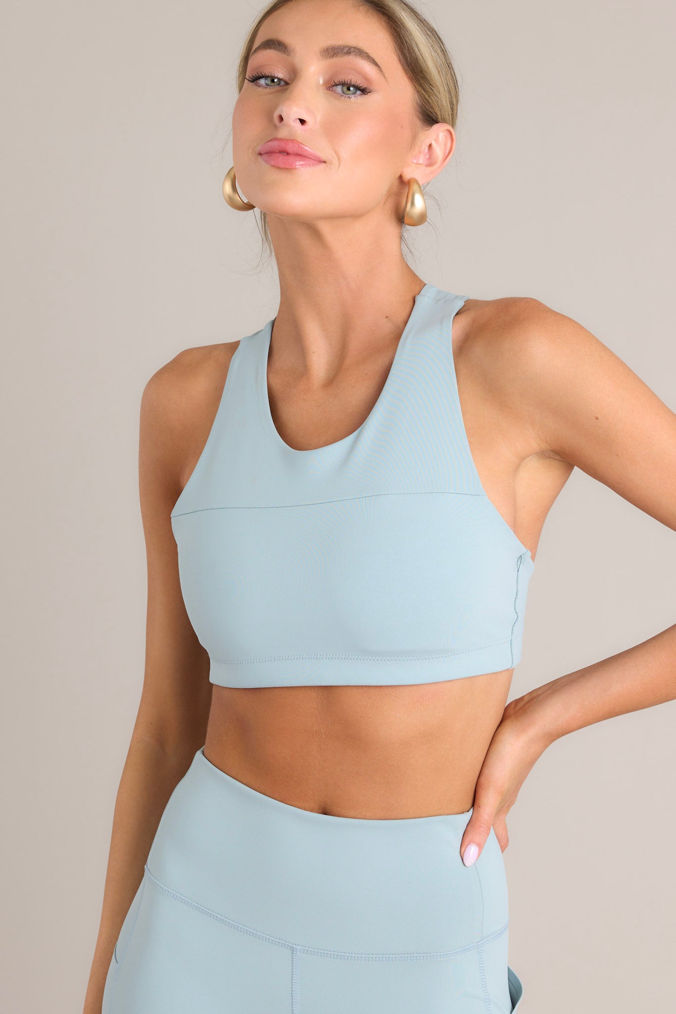 Front view of this sports bra that features a high neckline, removable pads, overlaying straps on the back, and a hook closure.