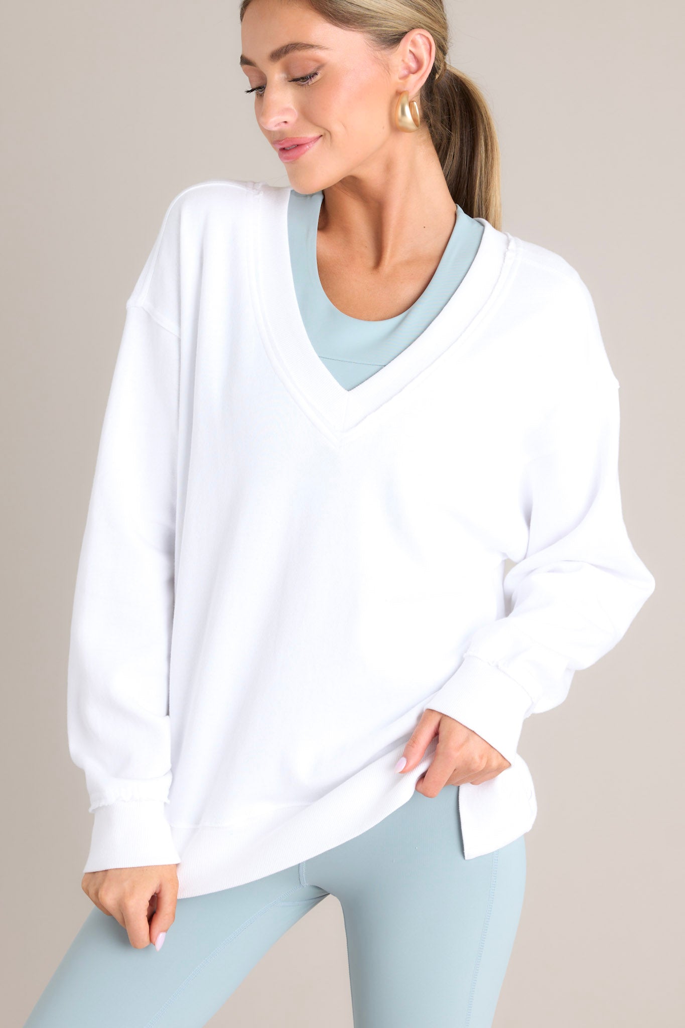 Angled view of this sweatshirt that features a v-neckline, a soft material, a split hemline, and ribbed cuffed sleeves.