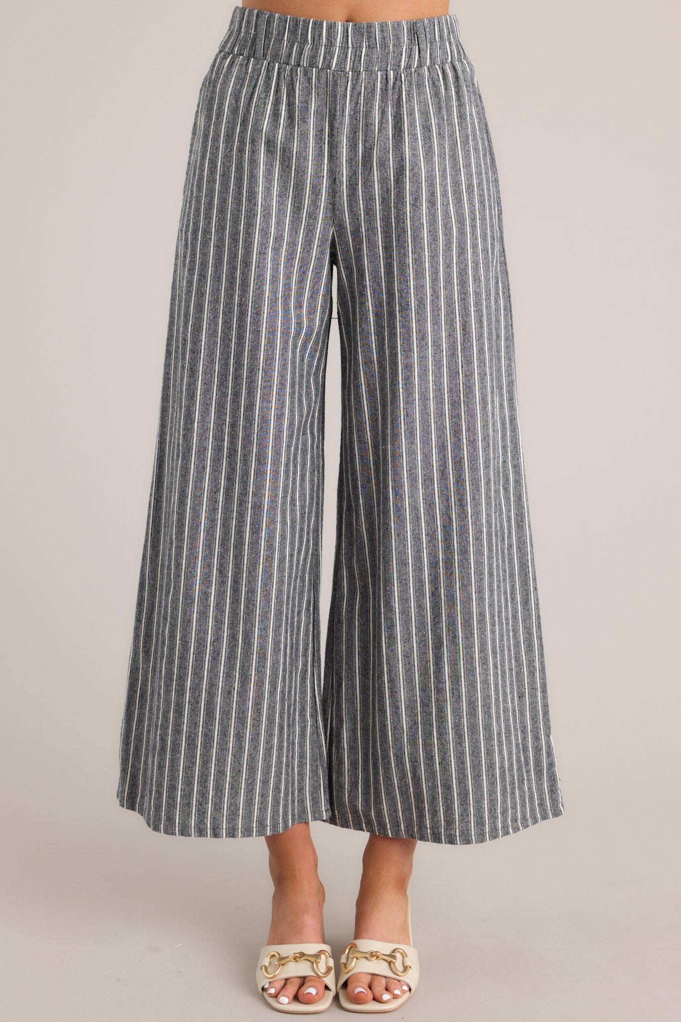 Front view of charcoal striped pants featuring a high rise with an elastic waistband, belt loops, an optional self-tie belt, functional pockets, and a wide leg design.