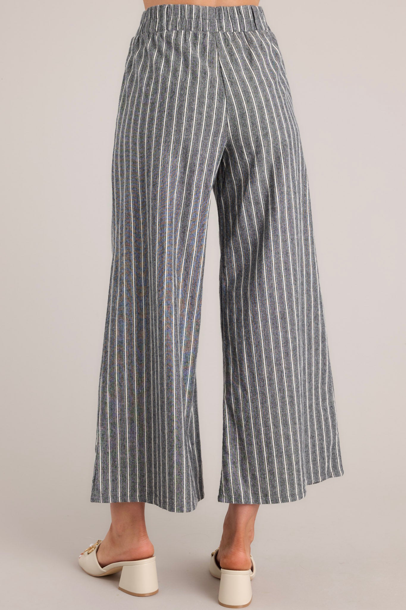 Back view of charcoal striped pants featuring belt loops, an elastic waistband, and a wide leg design.