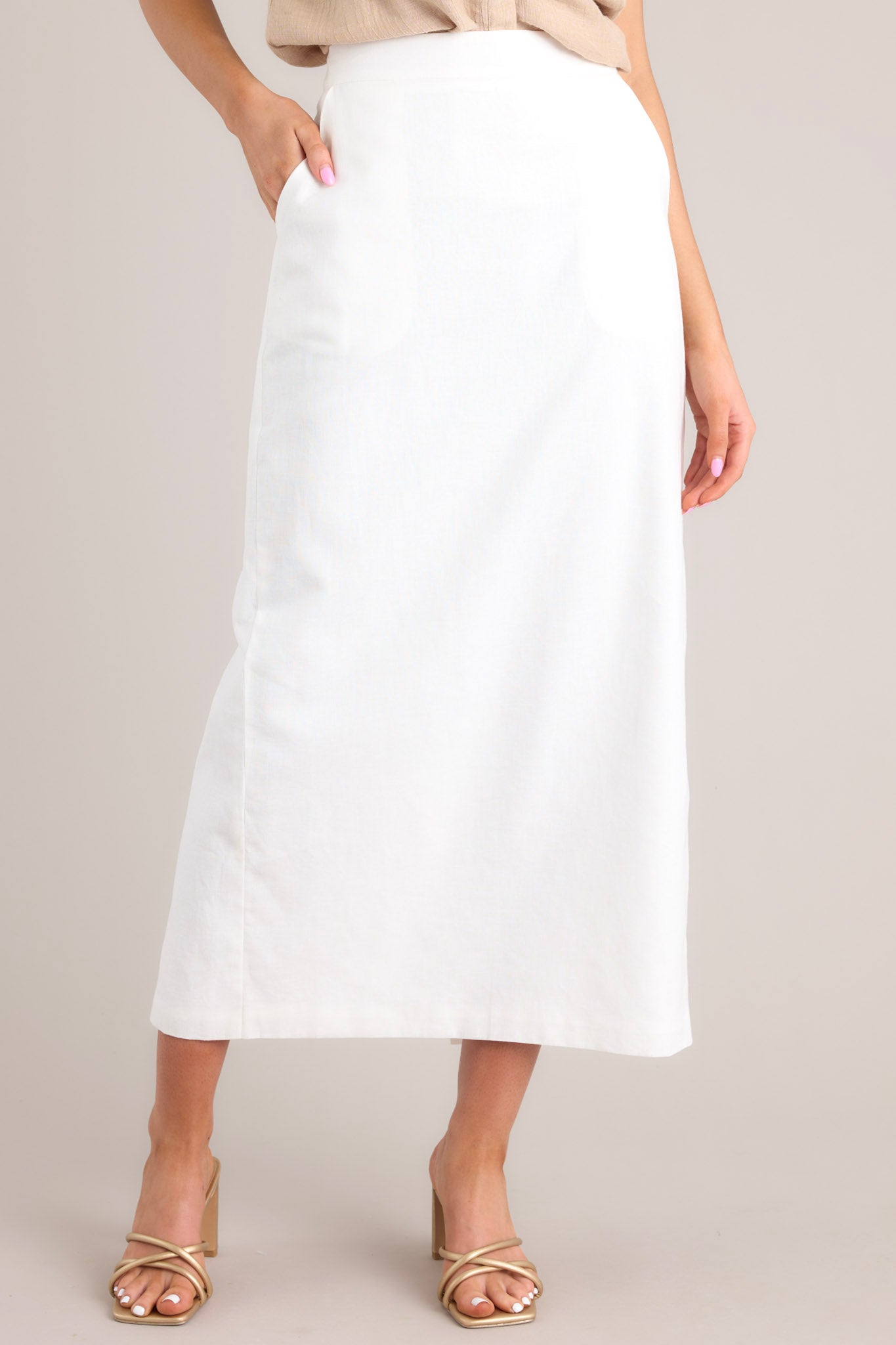 This white skirt features a high waisted design, a functional zipper in the back of the waist, functional hip pockets, and a slit in the back.