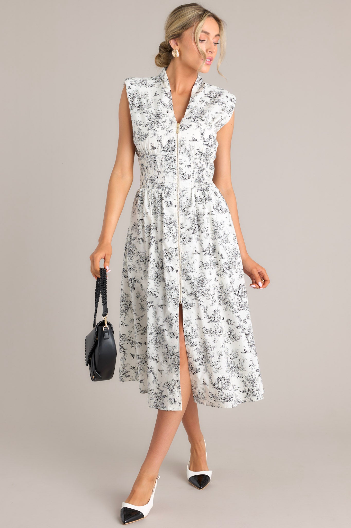 Full front view of this dress that features a v-neckline, shoulder padding, a zipper front, smocking in the waist, functional hip pockets, and a front slit.