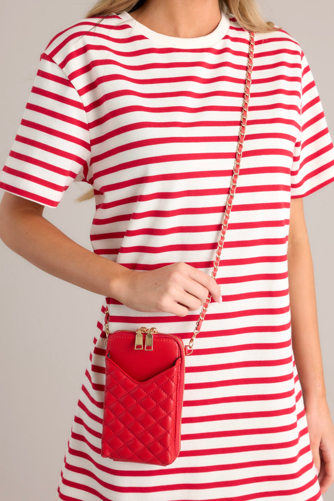  This red bag features gold hardware, a removable chain strap, a phone pocket, and multiple pockets inside.