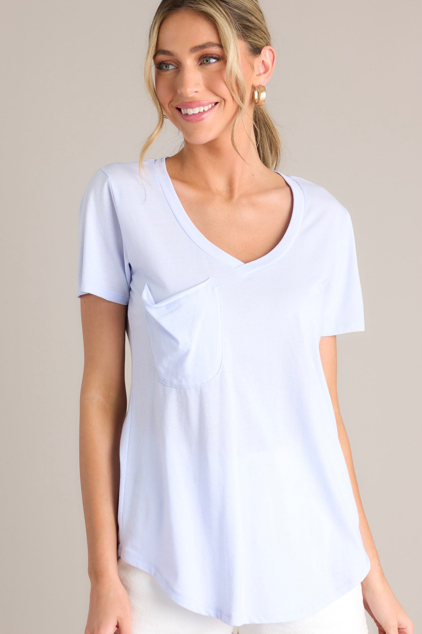 Angled close up view of this vibrant iris tee with a v-neckline, practical chest pocket, ultra-soft fabric, and a gracefully scooped hemline.