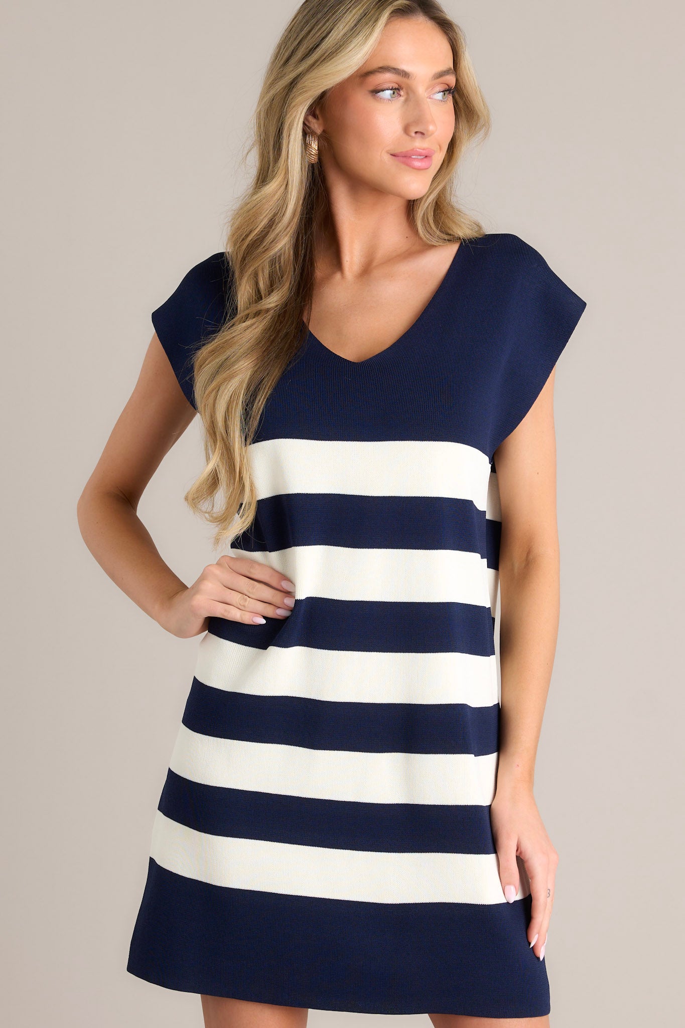 This navy stripe mini dress features a v-neckline, cap sleeves, a classic stripe pattern, a knit fabric, and a mini length.