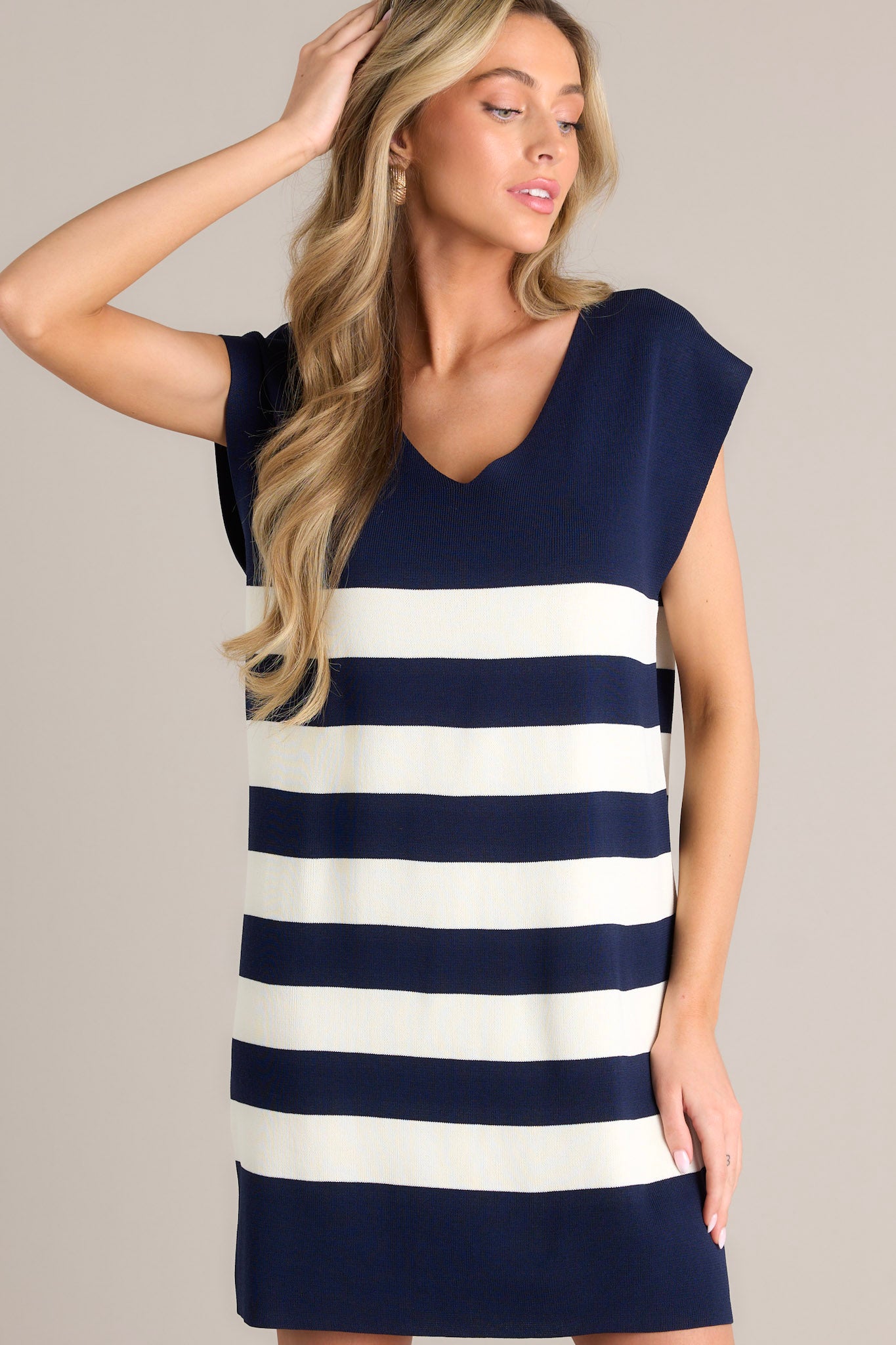 A close up view of this navy stripe mini dress that features a v-neckline, cap sleeves, a classic stripe pattern, a knit fabric, and a mini length.