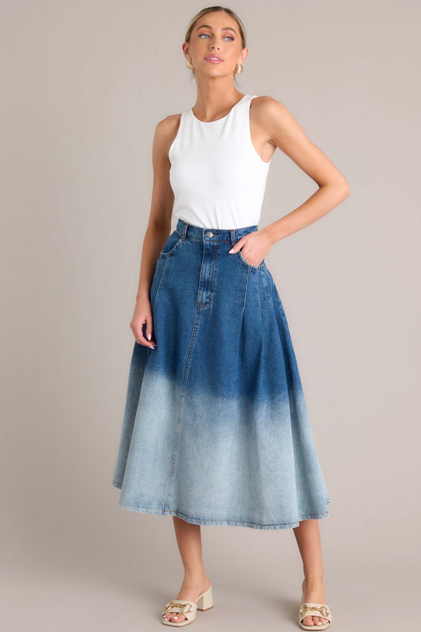 Full body view of this skirt that features a high waisted design, a classic button & zipper closure, belt loops, functional front pockets, subtle pleats, and an ombré gradient.