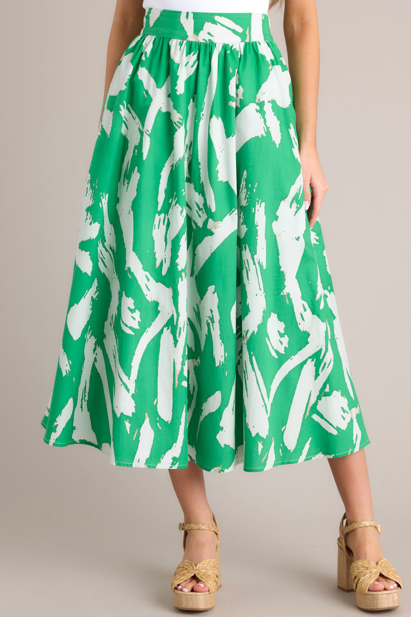 Close up view of this green skirt featuring a side zipper closure, functional waist pockets, and a gorgeous kelly green abstract print.