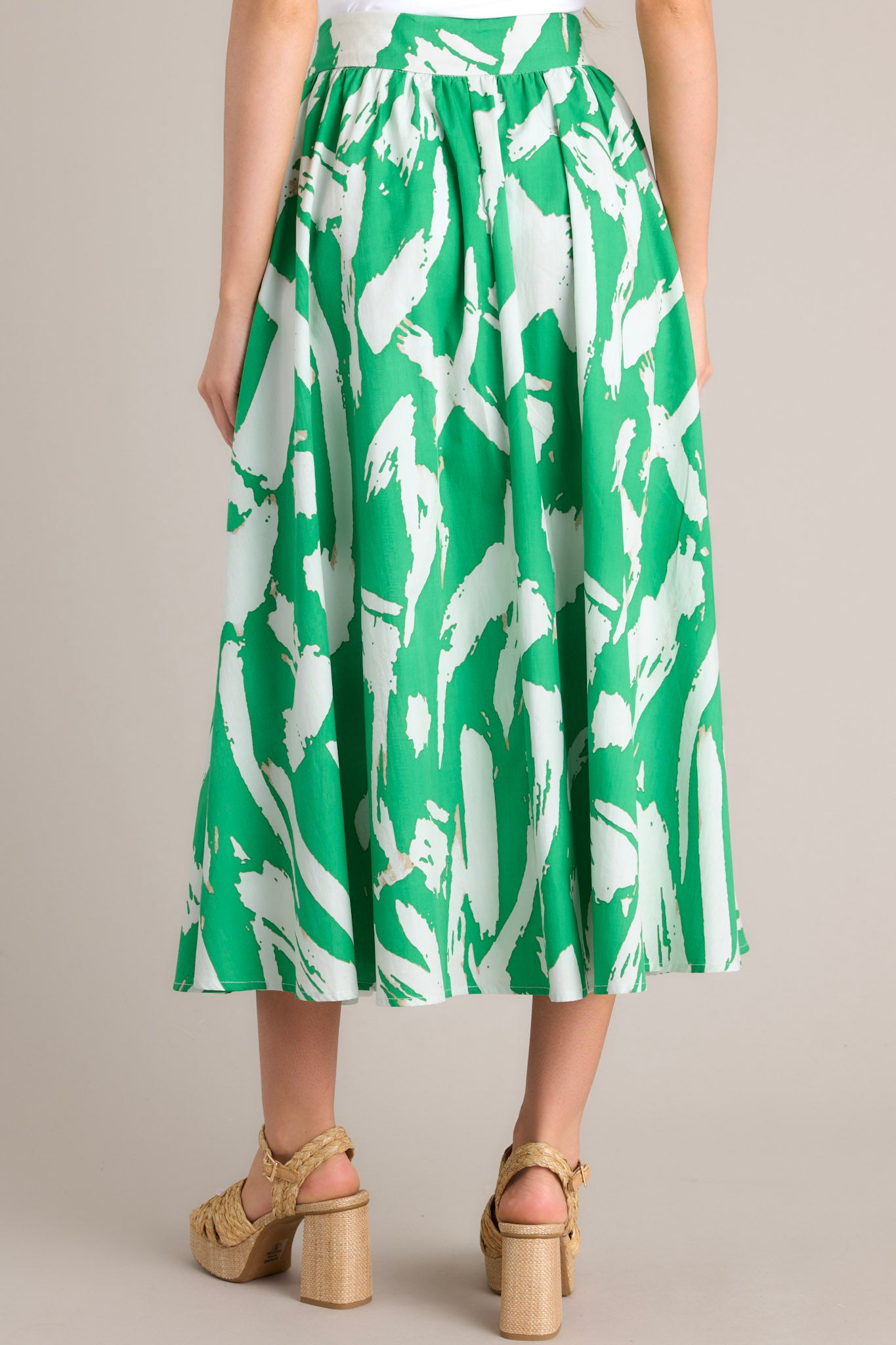 Back view of this green skirt featuring a side zipper closure, functional waist pockets, and a gorgeous kelly green abstract print.