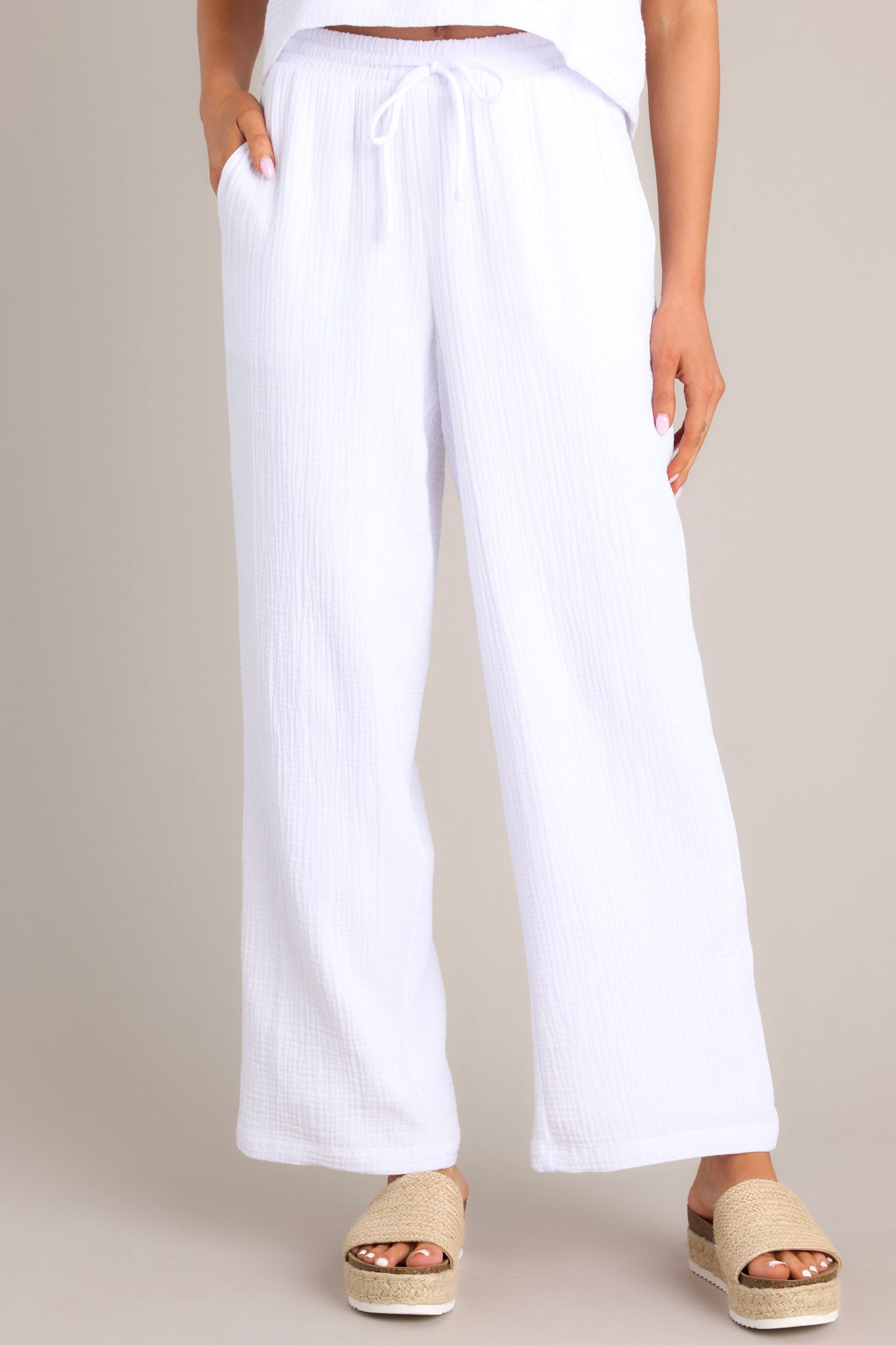 Front view of these pants that feature a high waisted design, an elastic waistband, a self-tie drawstring, functional hip pockets, and a wide leg.