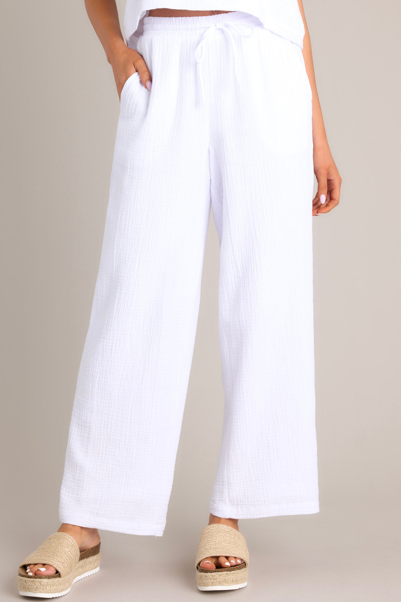 Full front view of these pants that feature a high waisted design, an elastic waistband, a self-tie drawstring, functional hip pockets, and a wide leg.