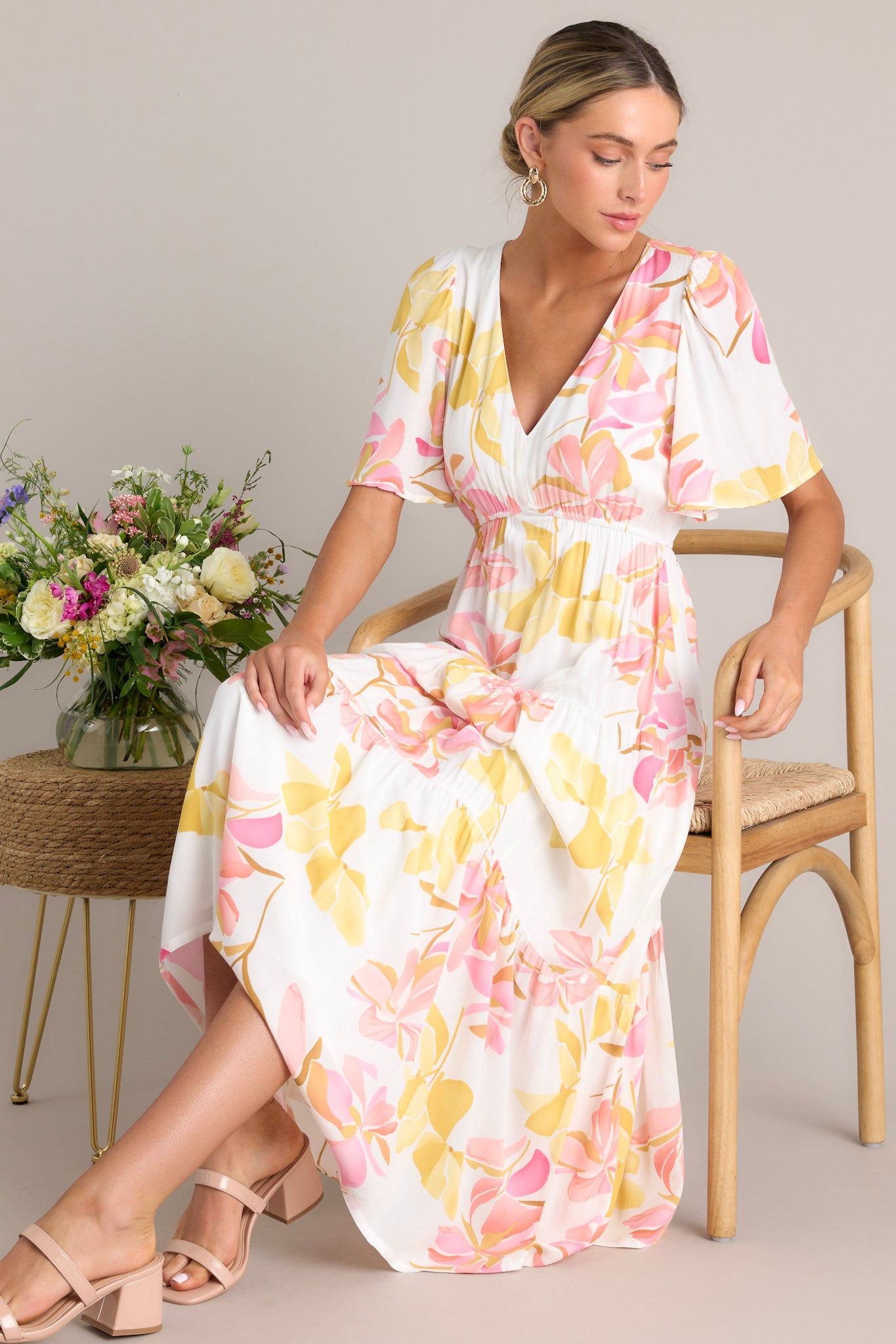 This floral maxi dress features a v-neckline, an elastic waistband, a tiered design, and short flutter sleeves.